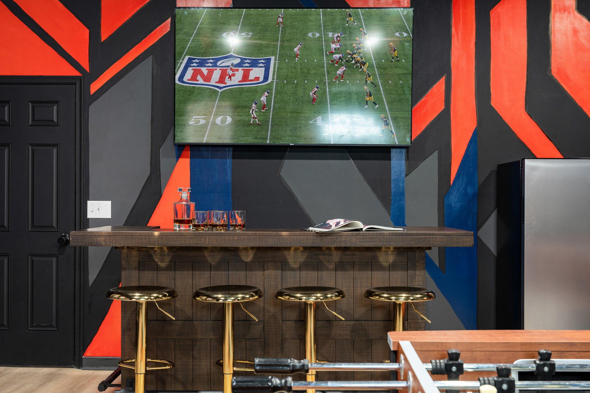 A stylish bar with seating and a big screen — the ideal spot for game-day viewing or evening cocktails