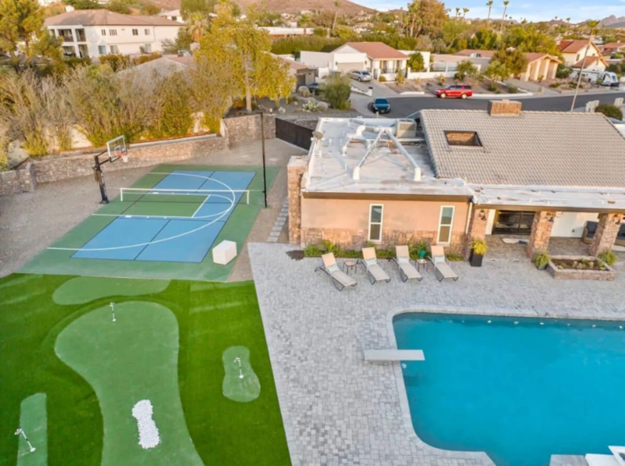 From above: putting green, sport court, pool, and mountain backdrop — a backyard built for every kind of fun.