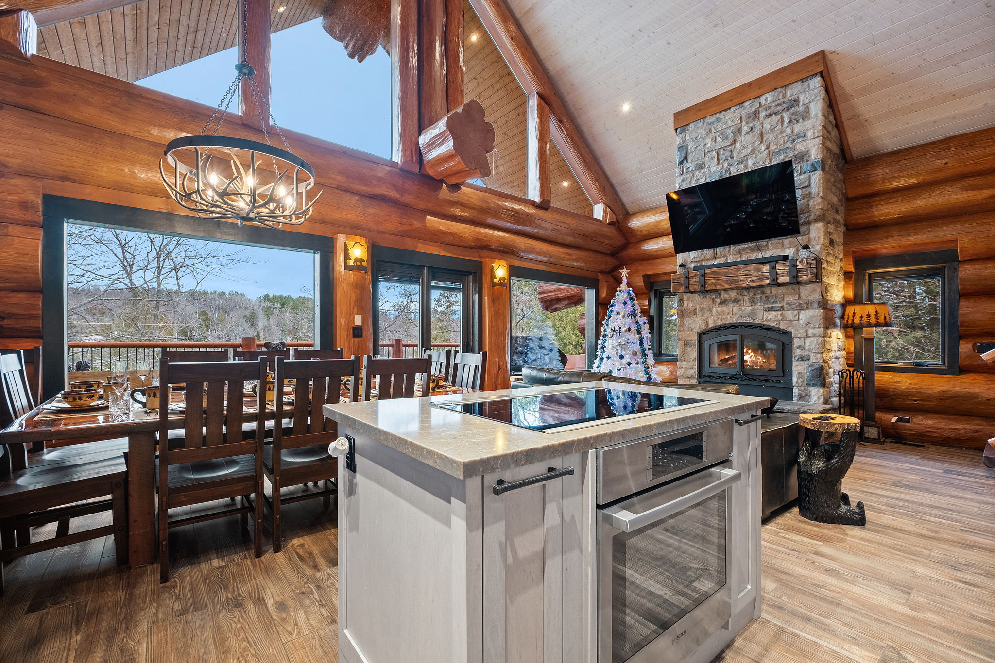 Beautiful dining space with seating for large groups, stone fireplace, and a fully equipped gourmet kitchen with island.