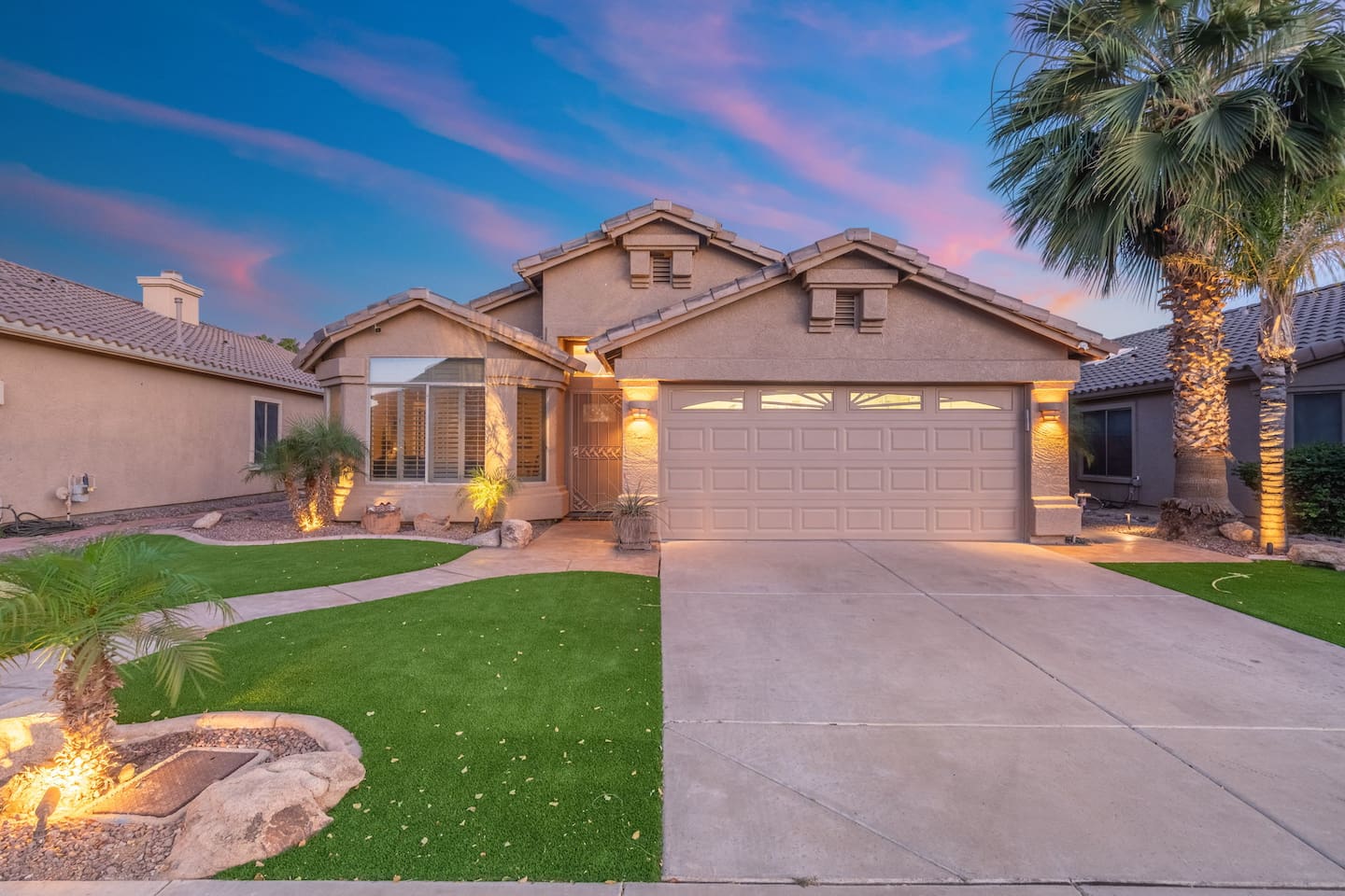 Your Arizona getaway awaits — a beautifully lit exterior with lush green lawn, mature palms, and welcoming curb appeal set the tone the moment you pull up.