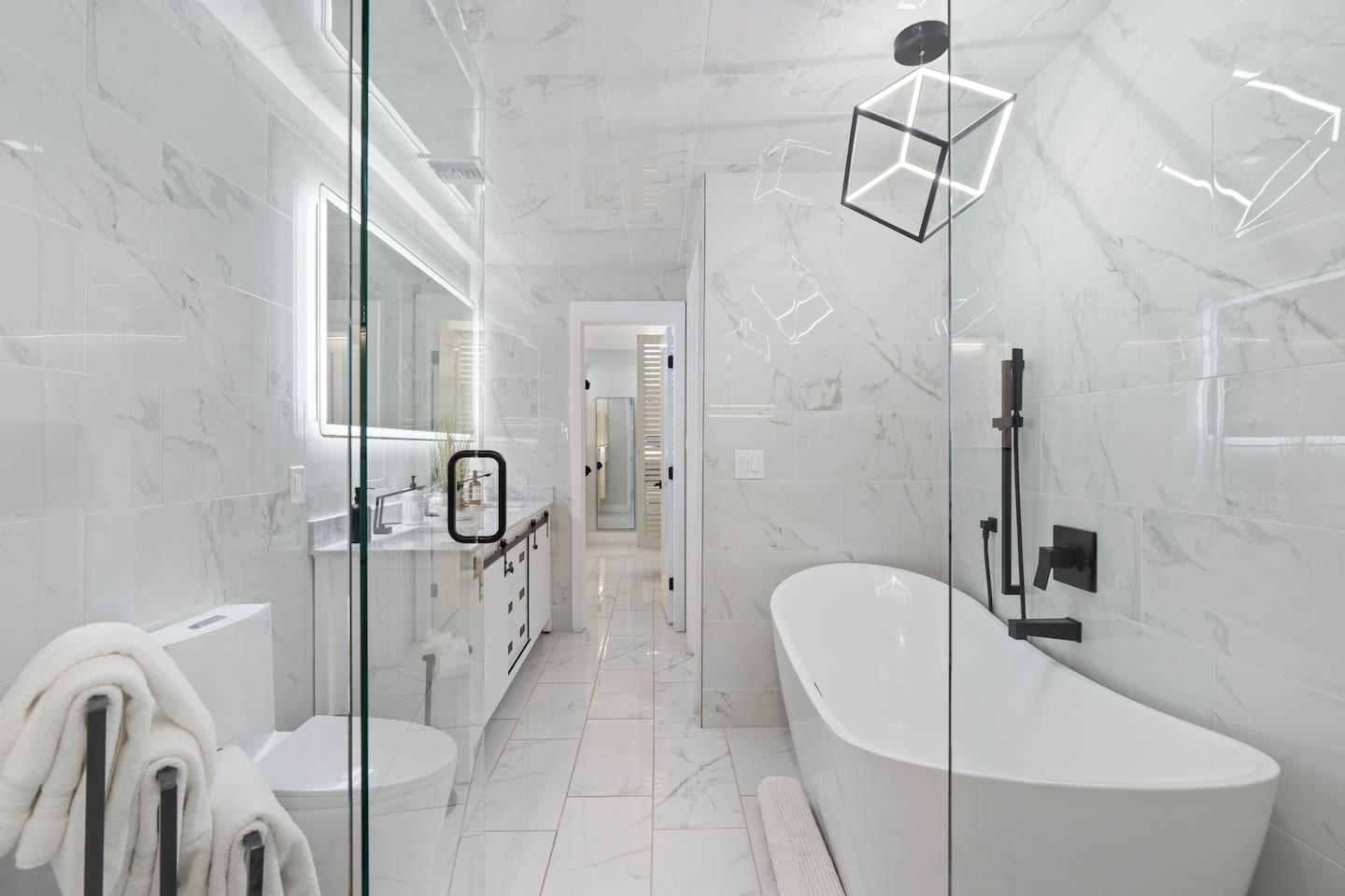 Wide-angle view showcasing the elegant tub, vanity, and entry to closet.

