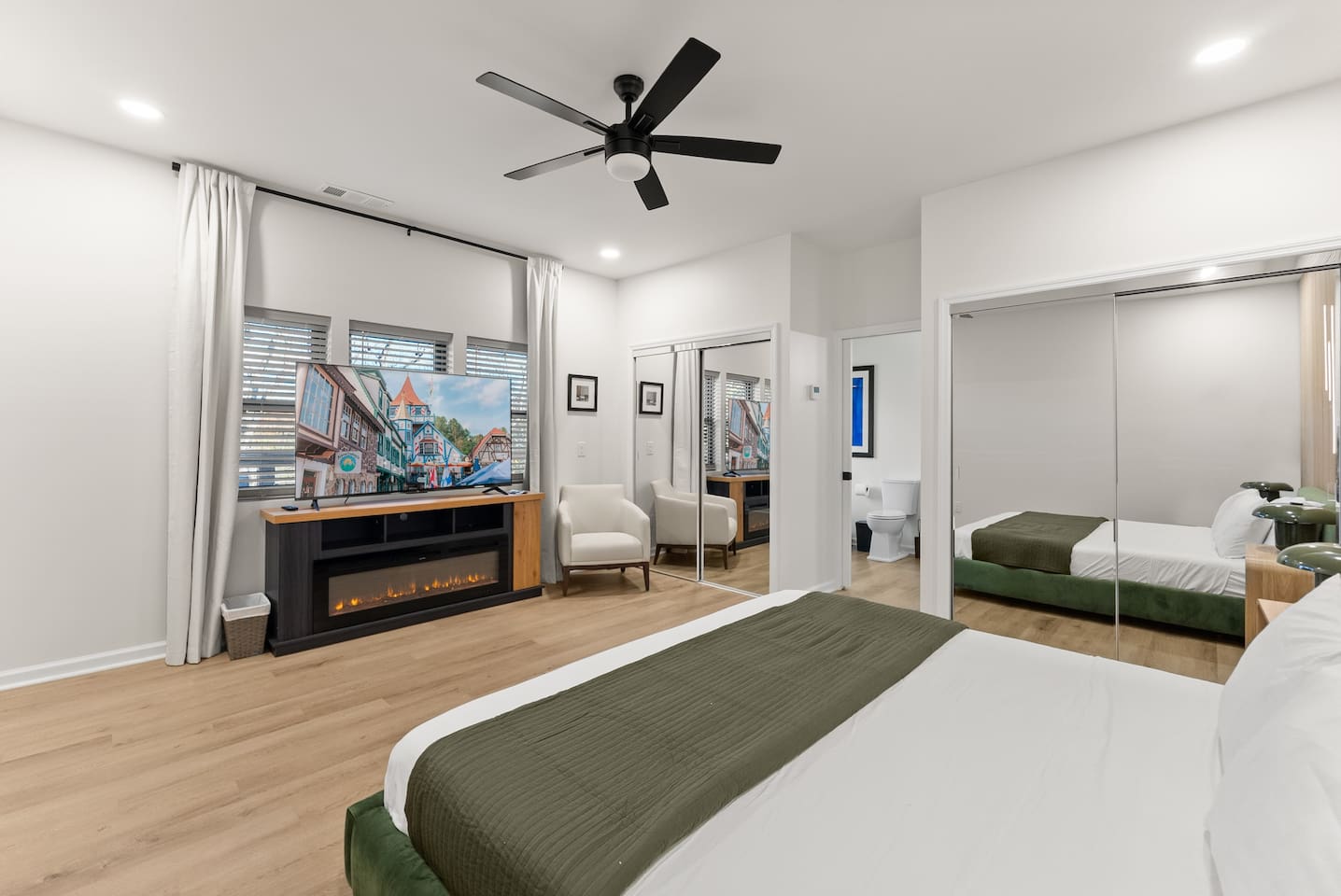 Master bedroom with a king bed, cozy electric fireplace, and a large TV—perfect for relaxing in comfort.