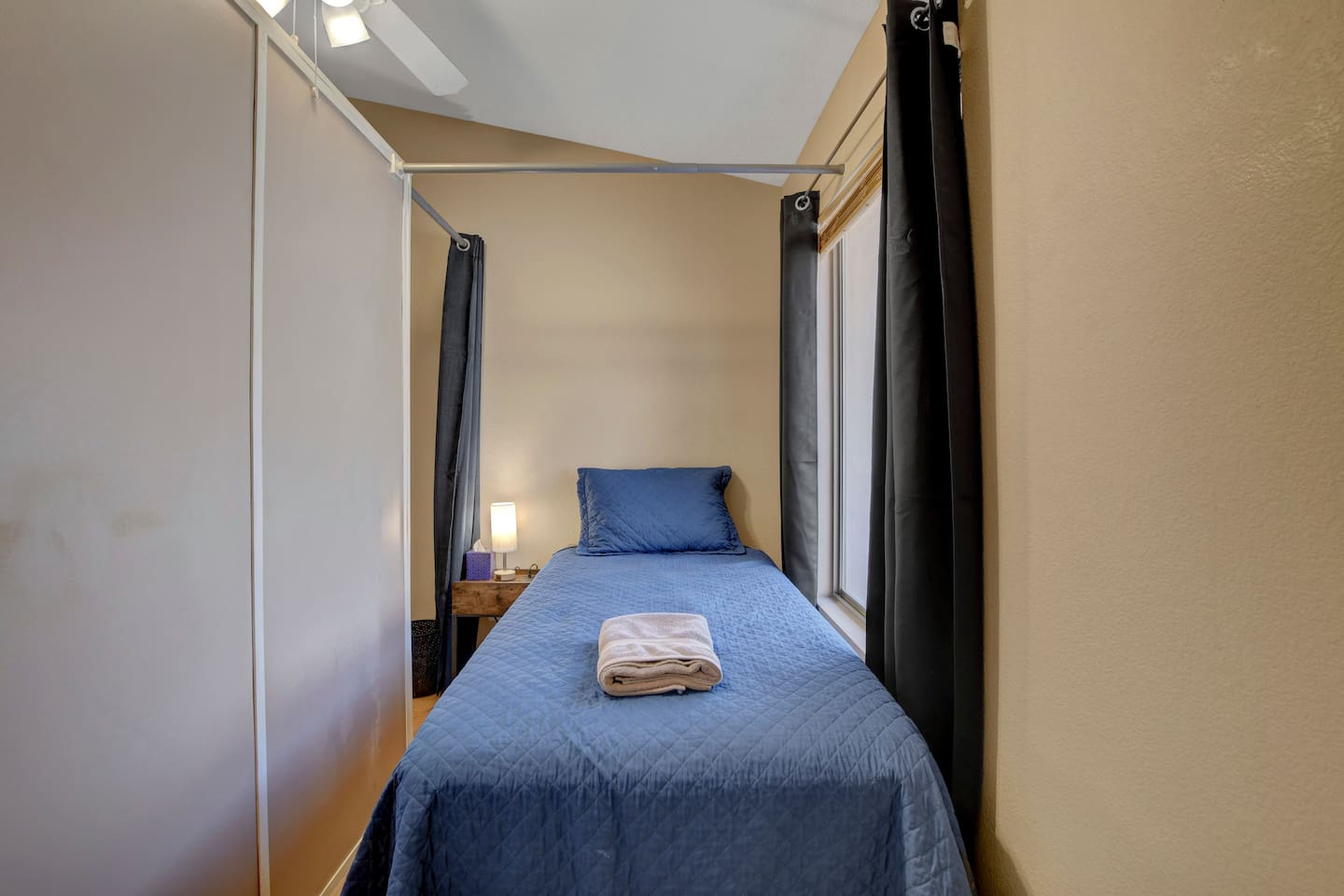 Cozy curtained twin nook with lamp, fan & fresh linens