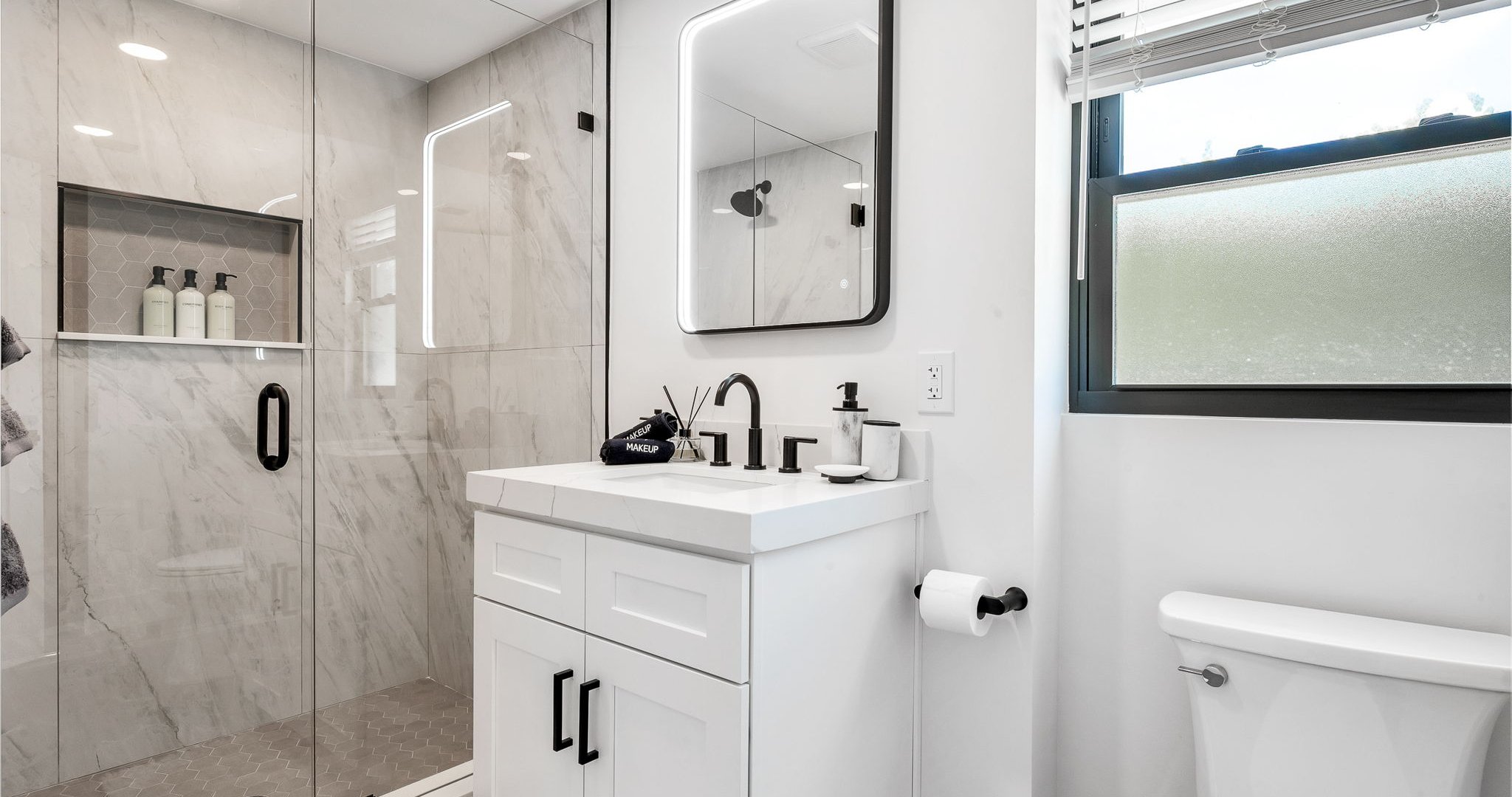 Step into a brand-new, spa-inspired primary bathroom featuring a sleek glass-enclosed walk-in shower with rainfall showerhead, designer vanity with LED mirror, and elegant finishes throughout.