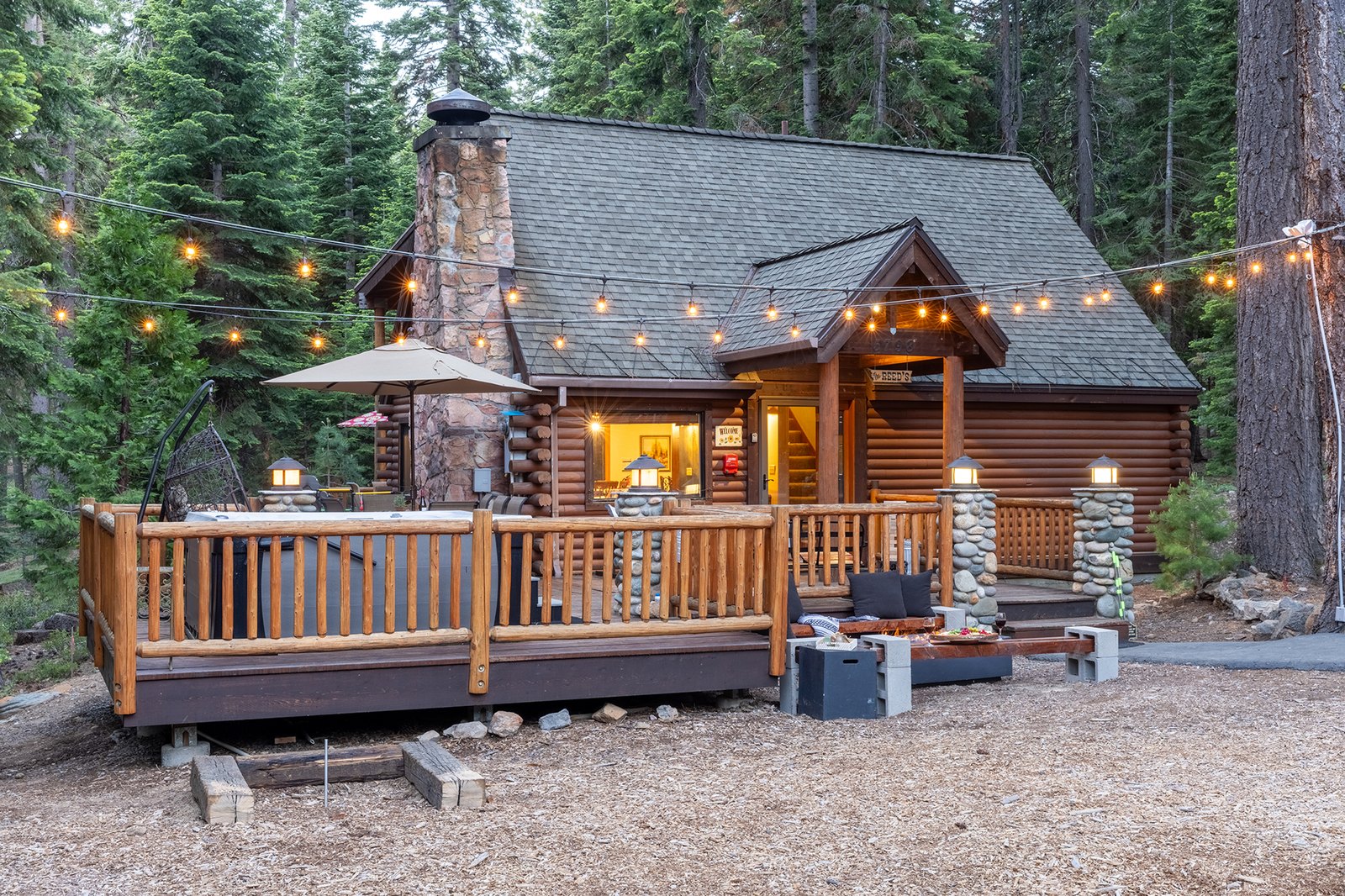 Pull up to this after a day on the trails — warm windows, string lights overhead, the hot tub and fire pit already calling your name.