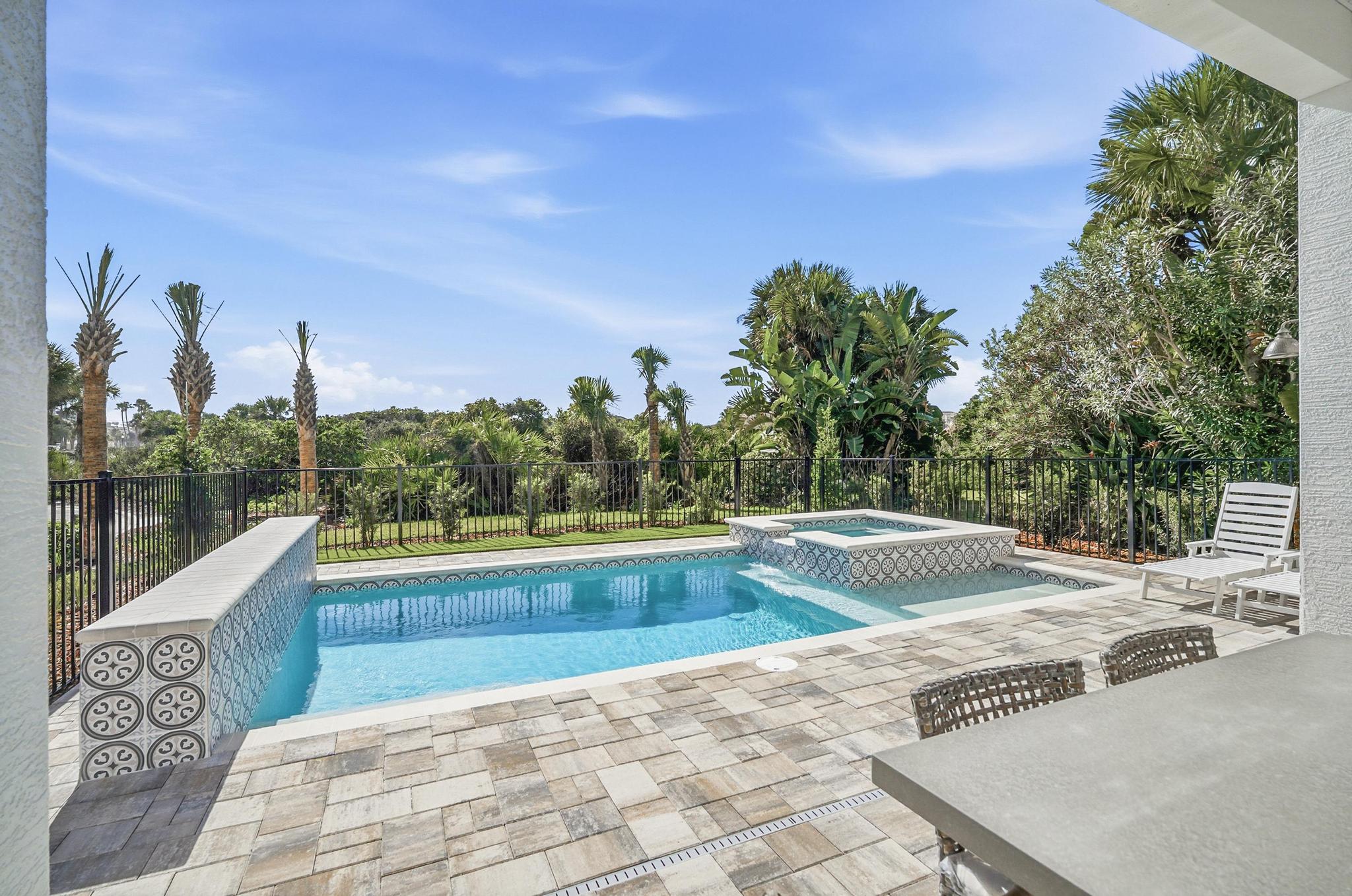 You step out with your morning coffee, the pavers still cool, and the pool glassy as the sky. A quick dip, then the spa bubbles while palms sway beyond the fence—your own private oasis between beach adventures.

