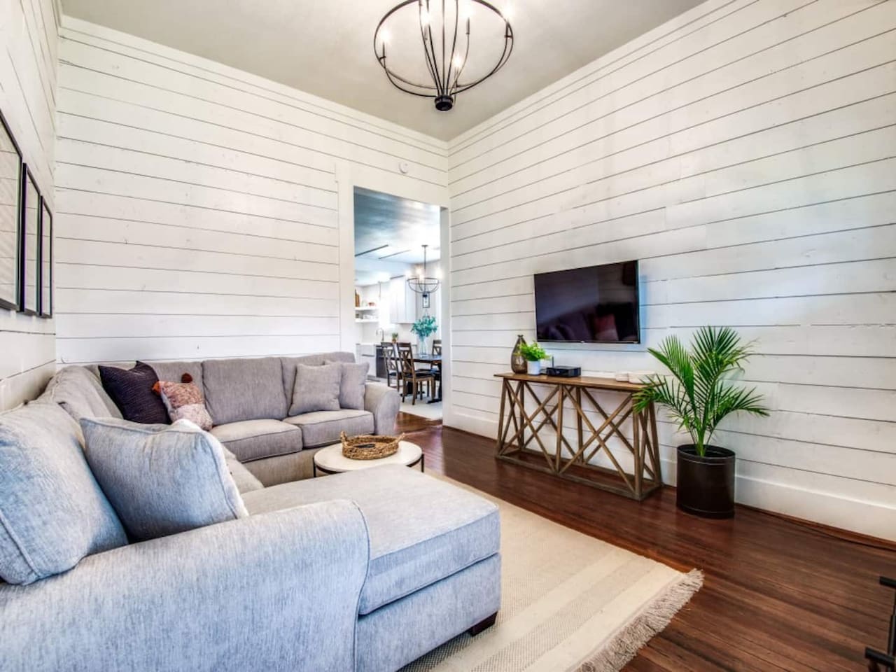 Shiplap accent wall, Smart TV, gray sectional, hardwood floors, and decorative chandelier. Modern farmhouse Airbnb in Aubrey TX sleeping up to 7. Minutes to The Milestone, Morgan Creek Barn, Lake Ray Roberts, and 30 min to Frisco.