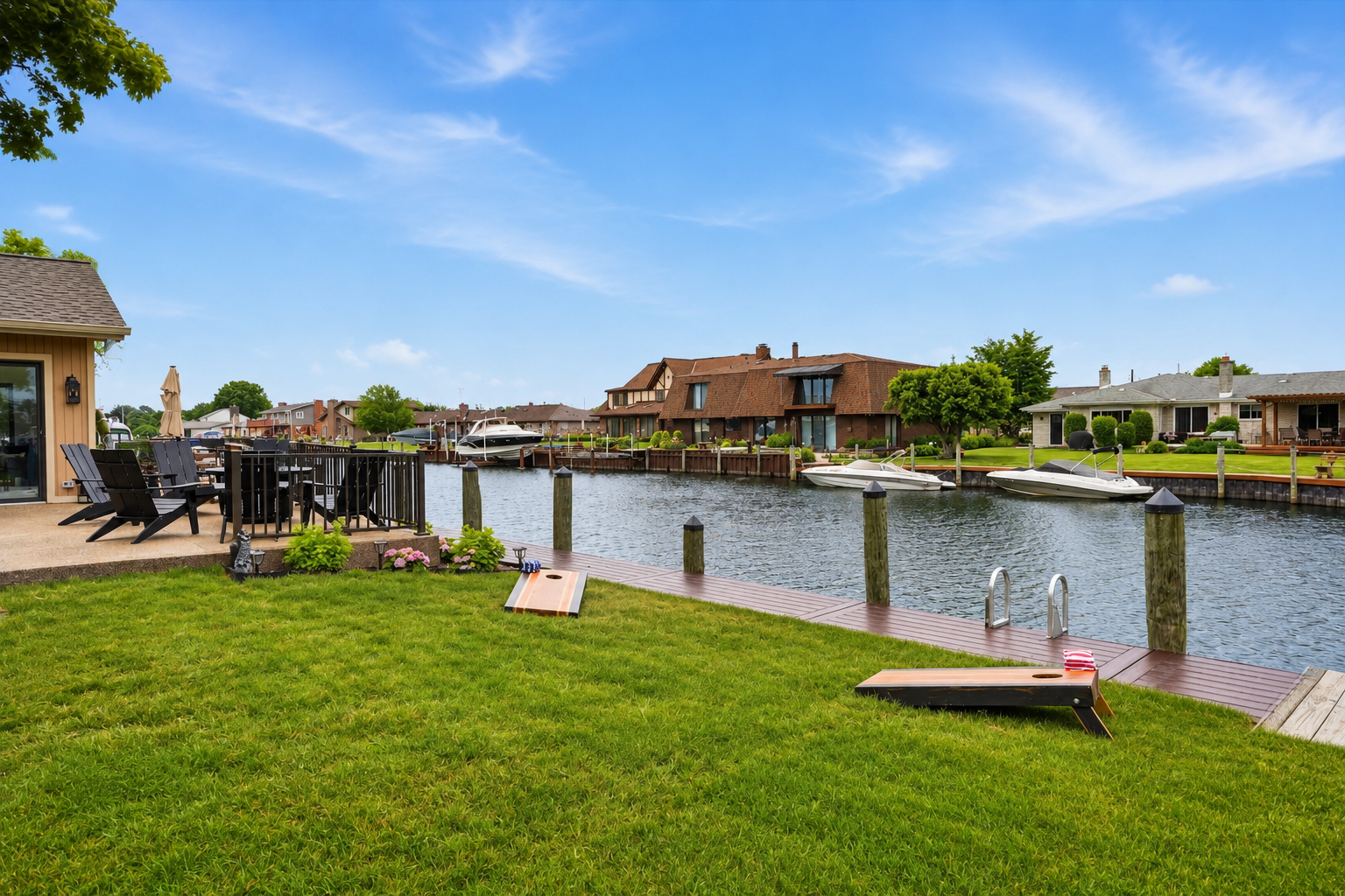 Waterfront lawn with cornhole setup and dock access, offering a peaceful outdoor space for games, relaxation, and scenic canal views.