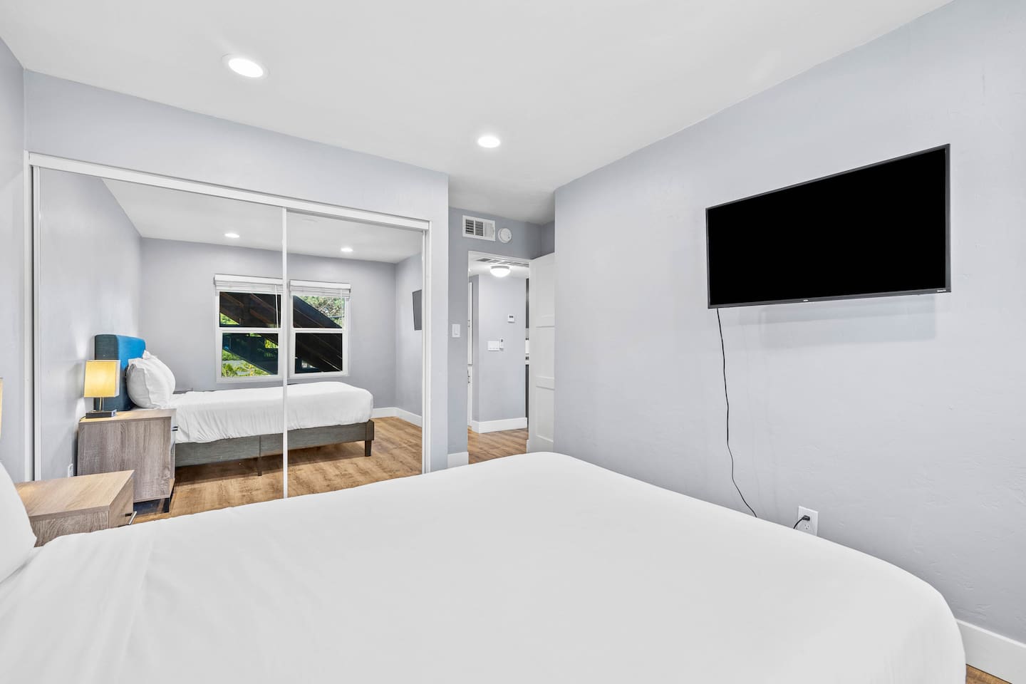 Relax in a stylish bedroom featuring a blue bed frame, elegant lamp, TV, and mirror. This cozy space combines comfort and charm, perfect for unwinding during your stay!