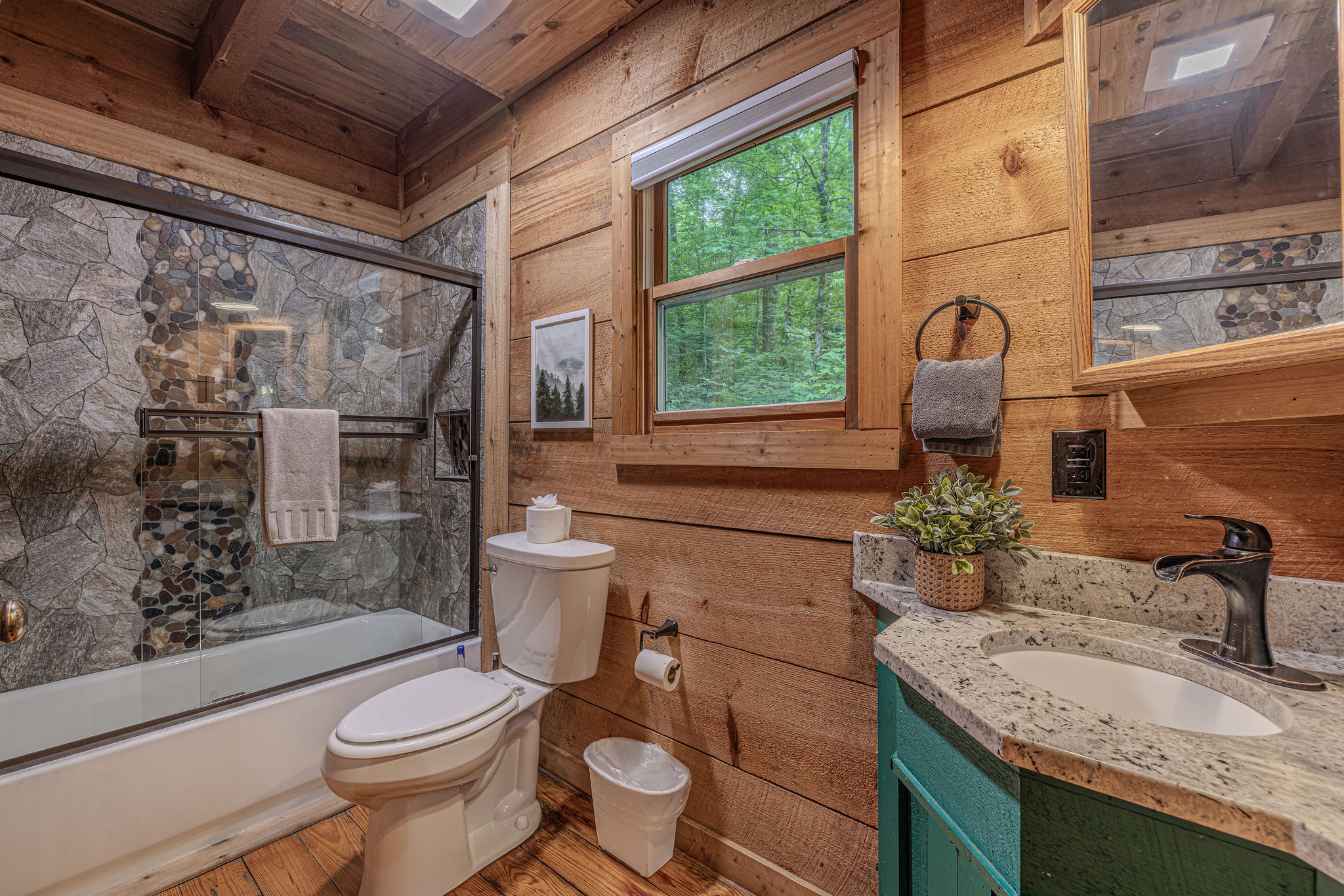 Stone tile shower, tub, and a window with tree views.
