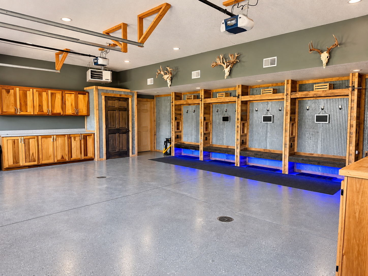 A clean, polished garage with epoxy flooring, built-in lockers for convenient storage, and subtle neon lighting beneath the lockers—an organized and welcoming space for your stay.