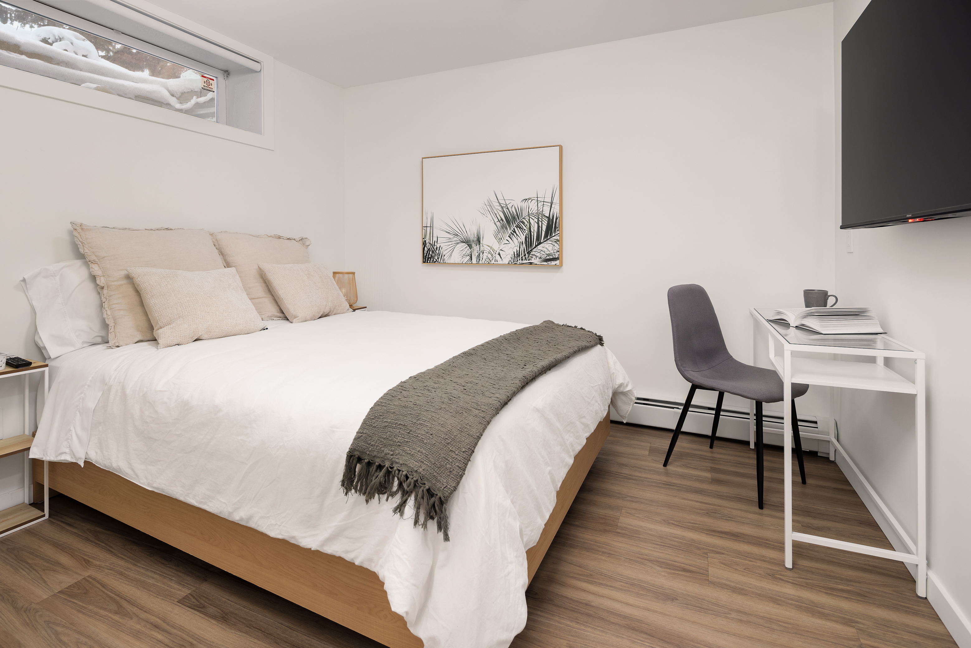 Second bedroom with queen bed, dedicated workspace, and wall-mounted Smart TV.