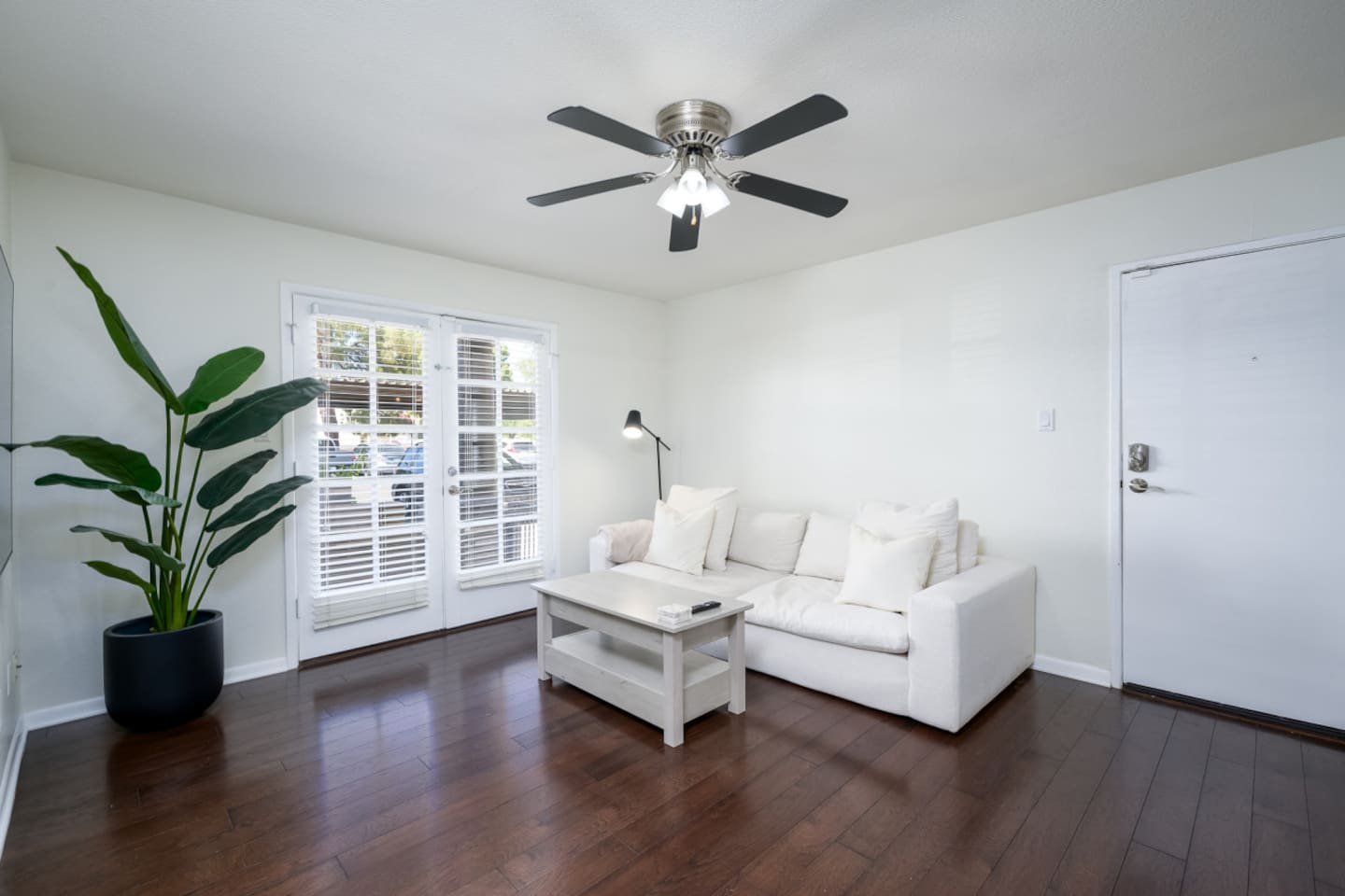 Open in-unit living area with sofa seating, Smart TV, and ceiling fan