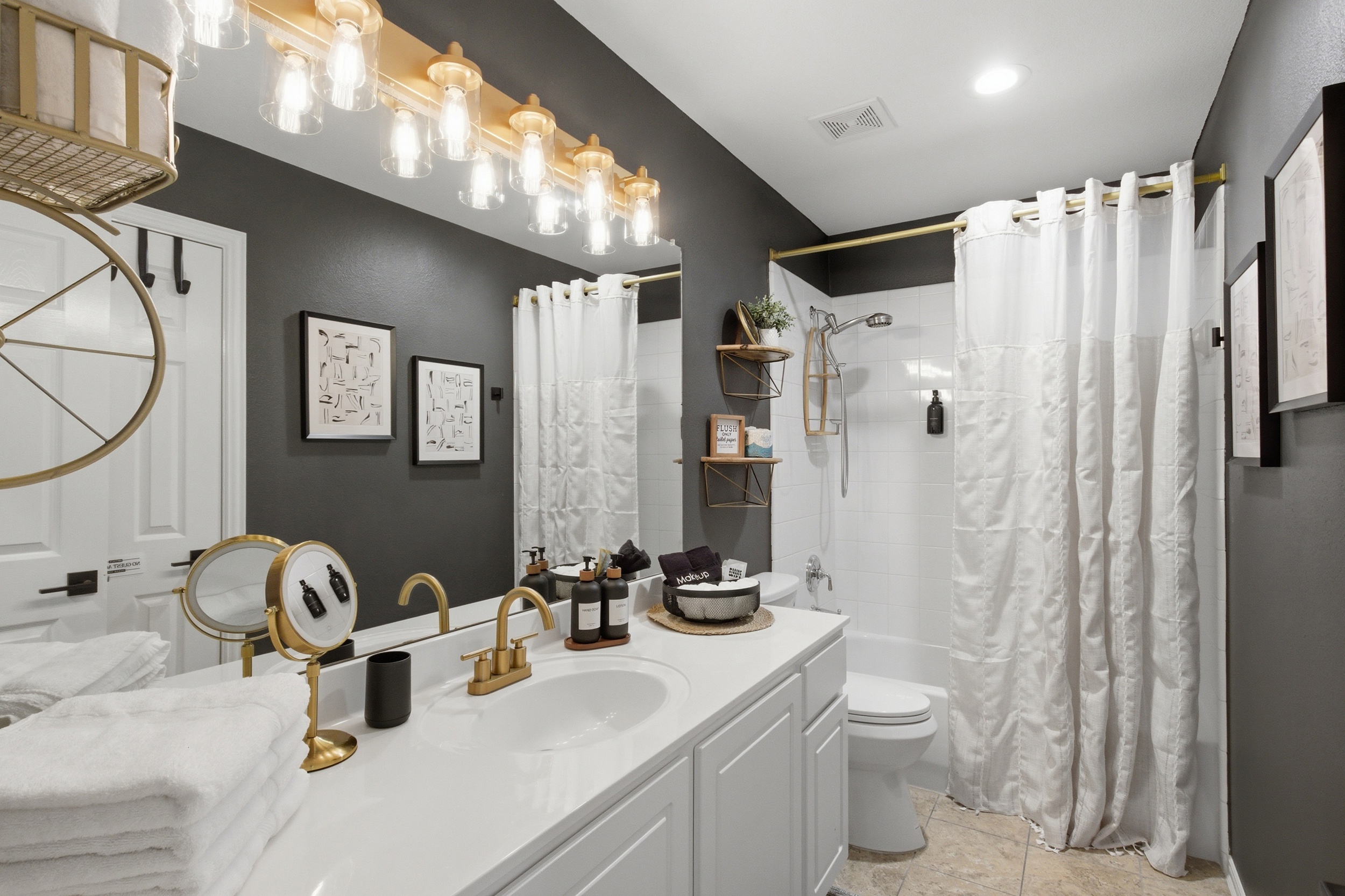 Guest Bathroom with a tub and shower combination, modern Vanity, and elegant gold fixtures. Stocked with essentials by Ginger Lily Farms.
