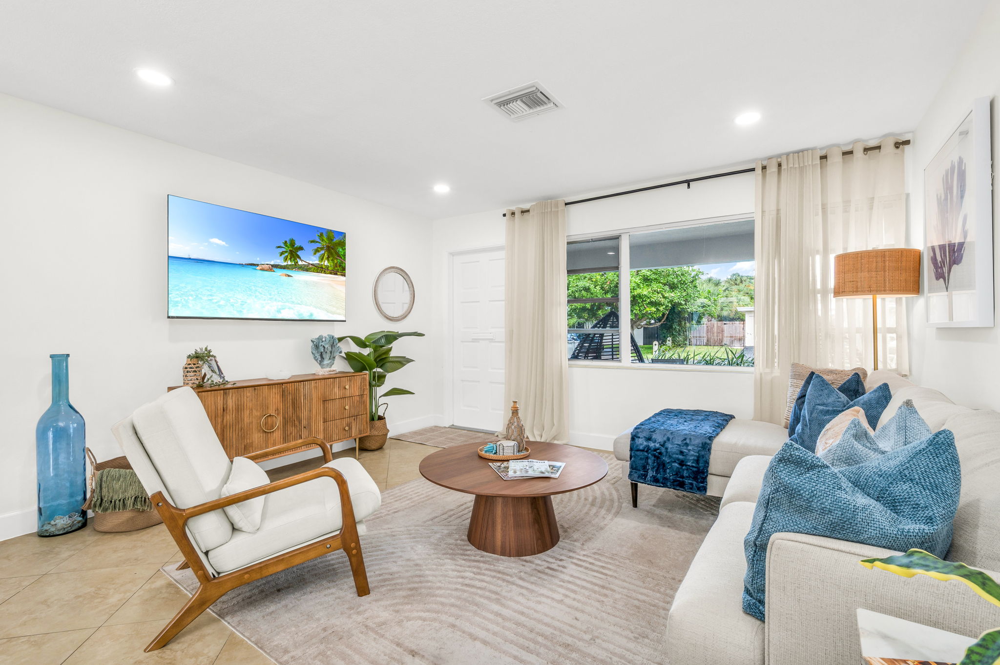 Bright and coastal-inspired, the living room features a plush sofa, stylish accent seating, a large Smart TV, and soothing ocean-toned décor—perfect for relaxing after a day at the beach.