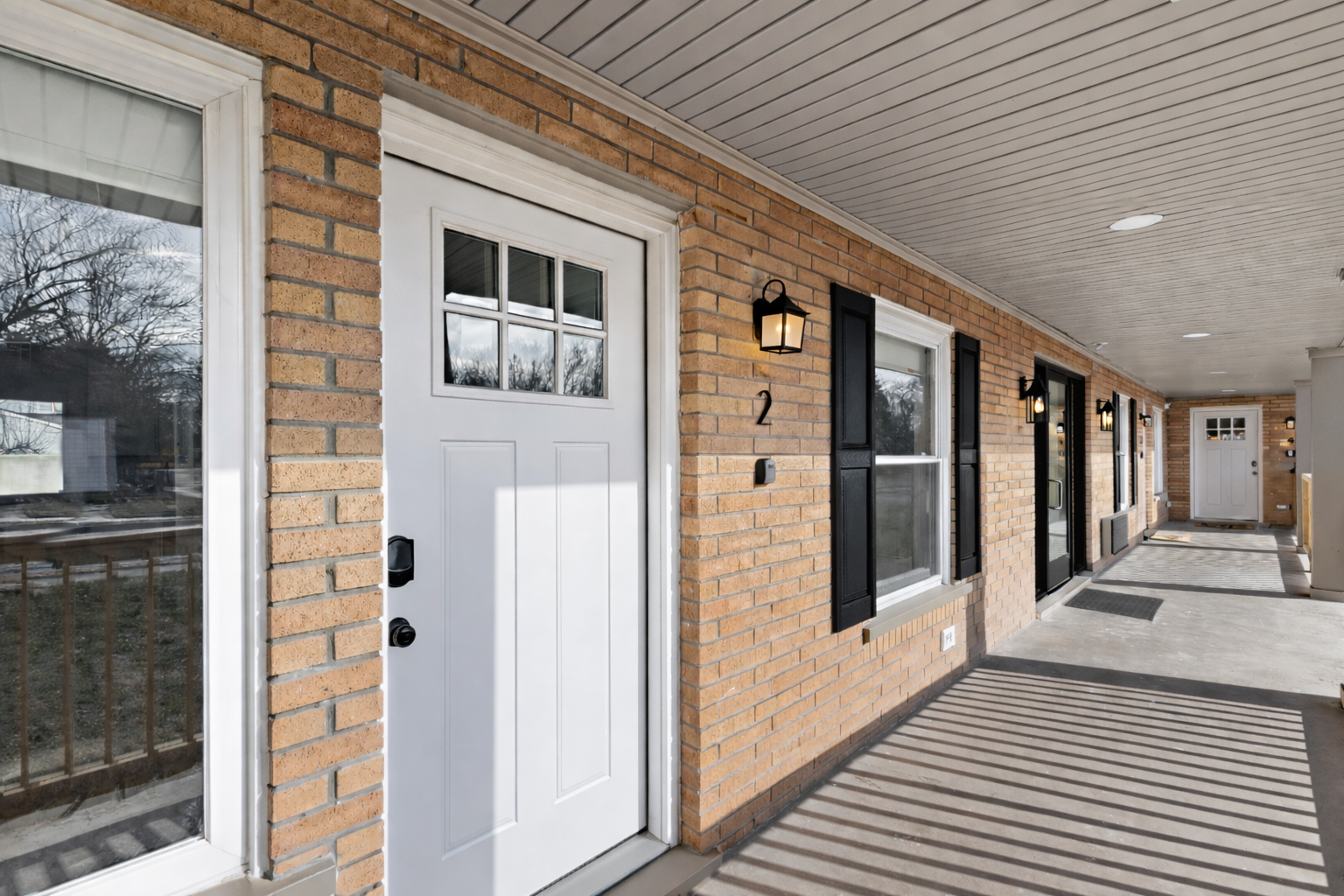 Inviting covered entry with a crisp white door, charming brick exterior, and soft lighting—offering a warm, private welcome from the moment you arrive.