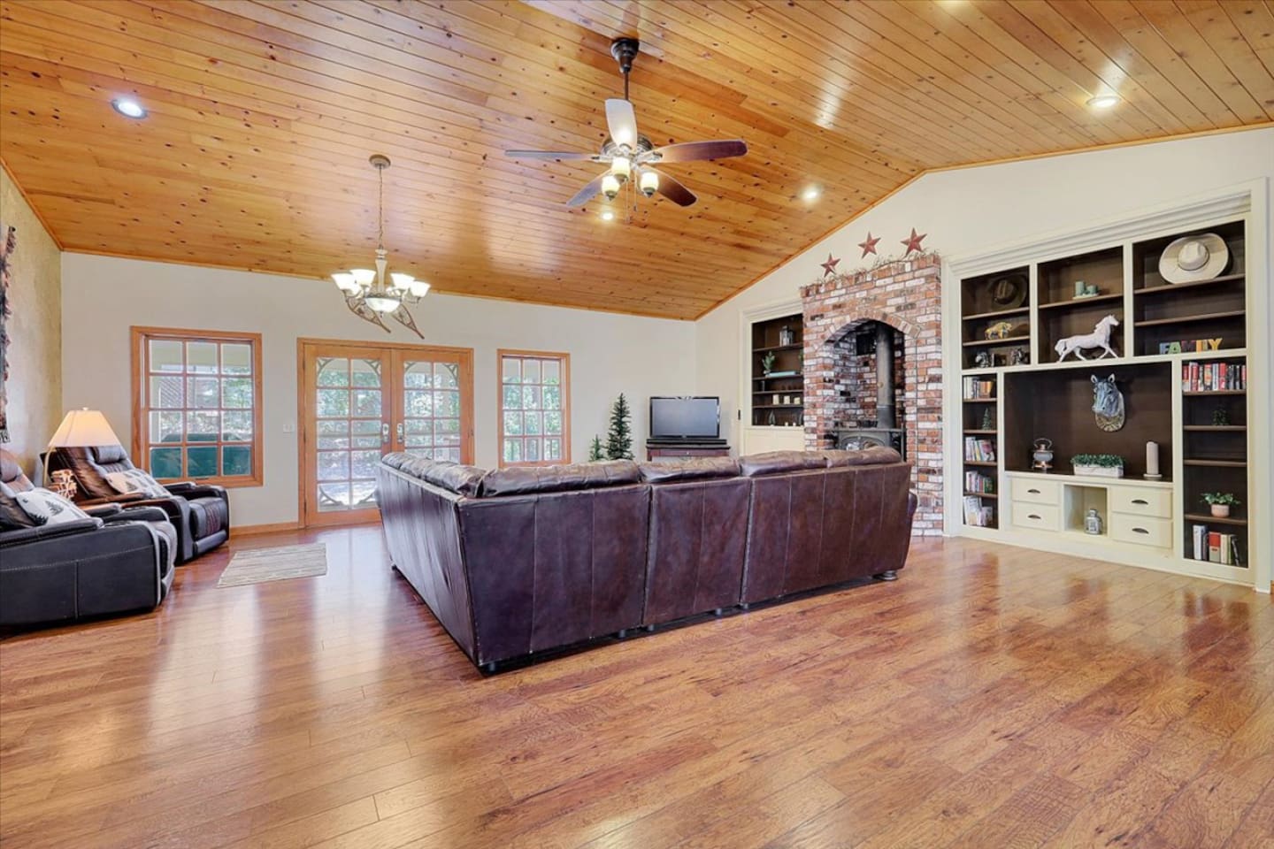 Living room with wood ceilings, leather seating, built-in shelves, and lots of open floor space.
