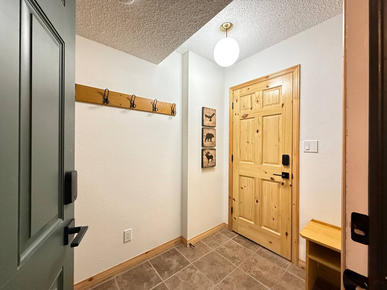 Efficient Entryway Storage: Compact and functional entrance at the Kimberley townhouse, featuring a wooden coat rack with ample hooks and floor space for boots.