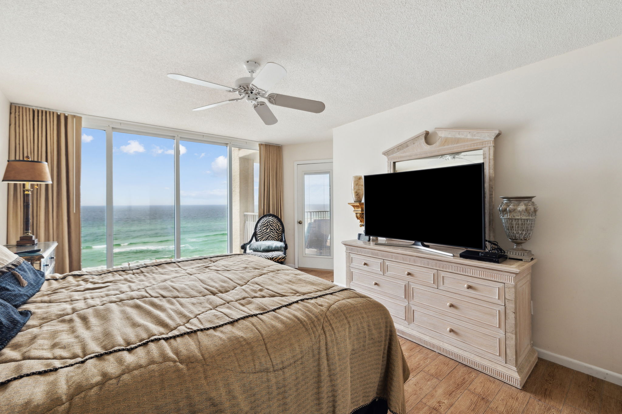 Master king suite bedroom with floor to ceiling windows showcasing the beautiful Emerald Gulf waters, balcony access from bedroom and en suite bathroom