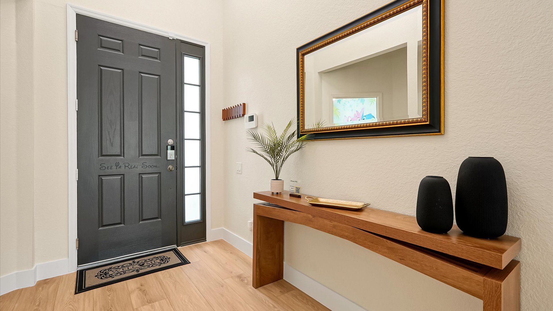 Front Entry: Welcoming entrance to Motunui Villa with a modern wood console, decorative mirror and convenient key hooks.