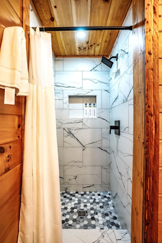 Cozy yet contemporary master bathroom with pristine white-tiled standing shower, offering a spa-inspired cabin bathroom retreat and serene mountain getaway vibes.