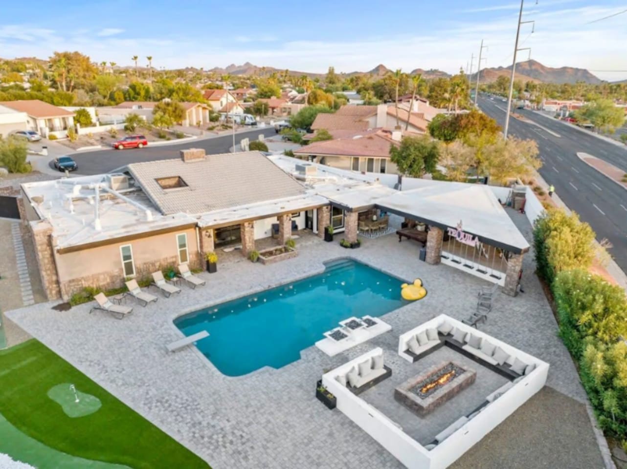 An aerial view reveals it all — pool, putting green, fire pit lounge, and mountain views in one incredible backyard.