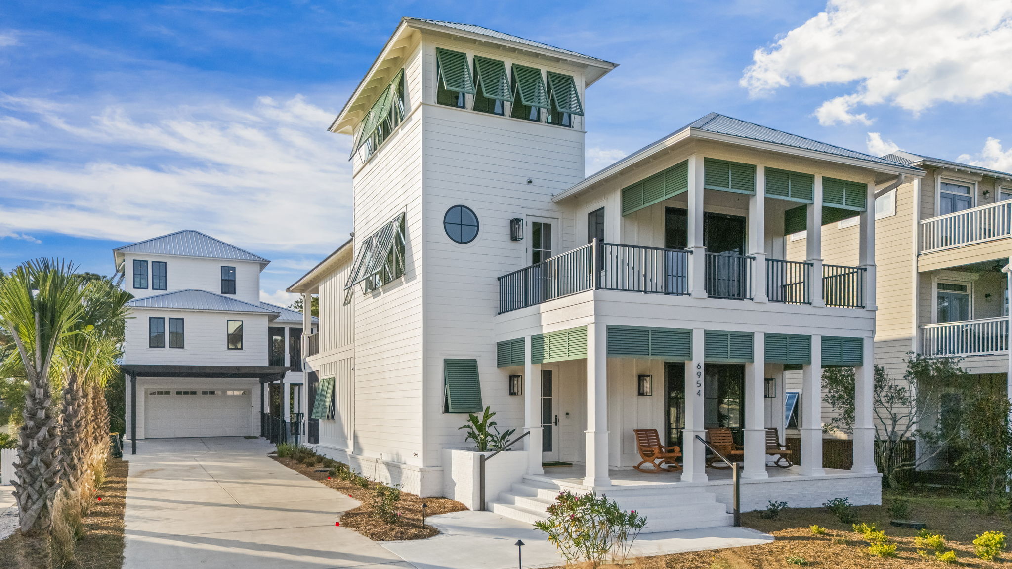 Magnolia Mooring’s front exterior showcases timeless coastal design with crisp white siding, classic Bahama shutters, and double front porches that invite you to slow down and settle in. A generous driveway offers easy parking, with the guest house tu