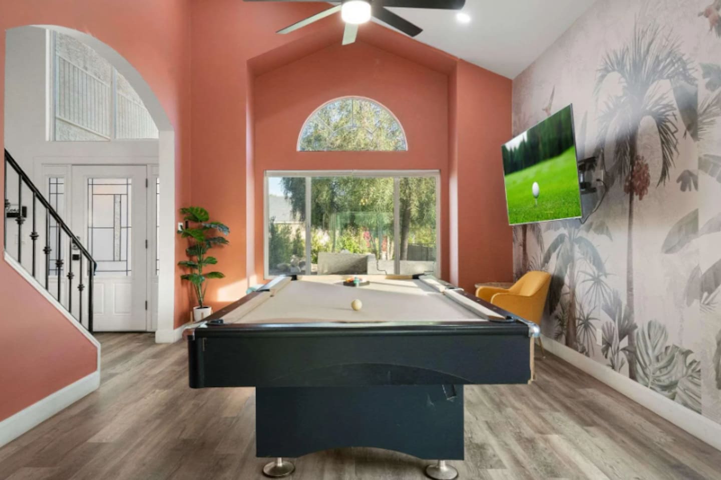 Game room with pool table, coral accent walls, botanical wallpaper, and floor-to-ceiling views.