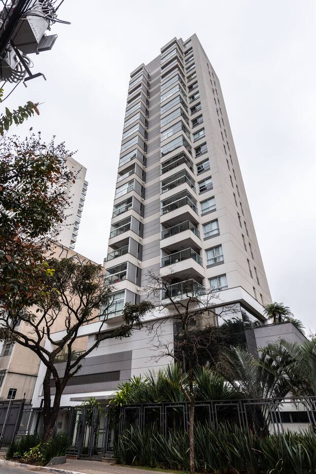 Fachada moderna do condomínio Homelike Pinheiros, com segurança 24h e localização privilegiada próxima à Av. Faria Lima e metrô.