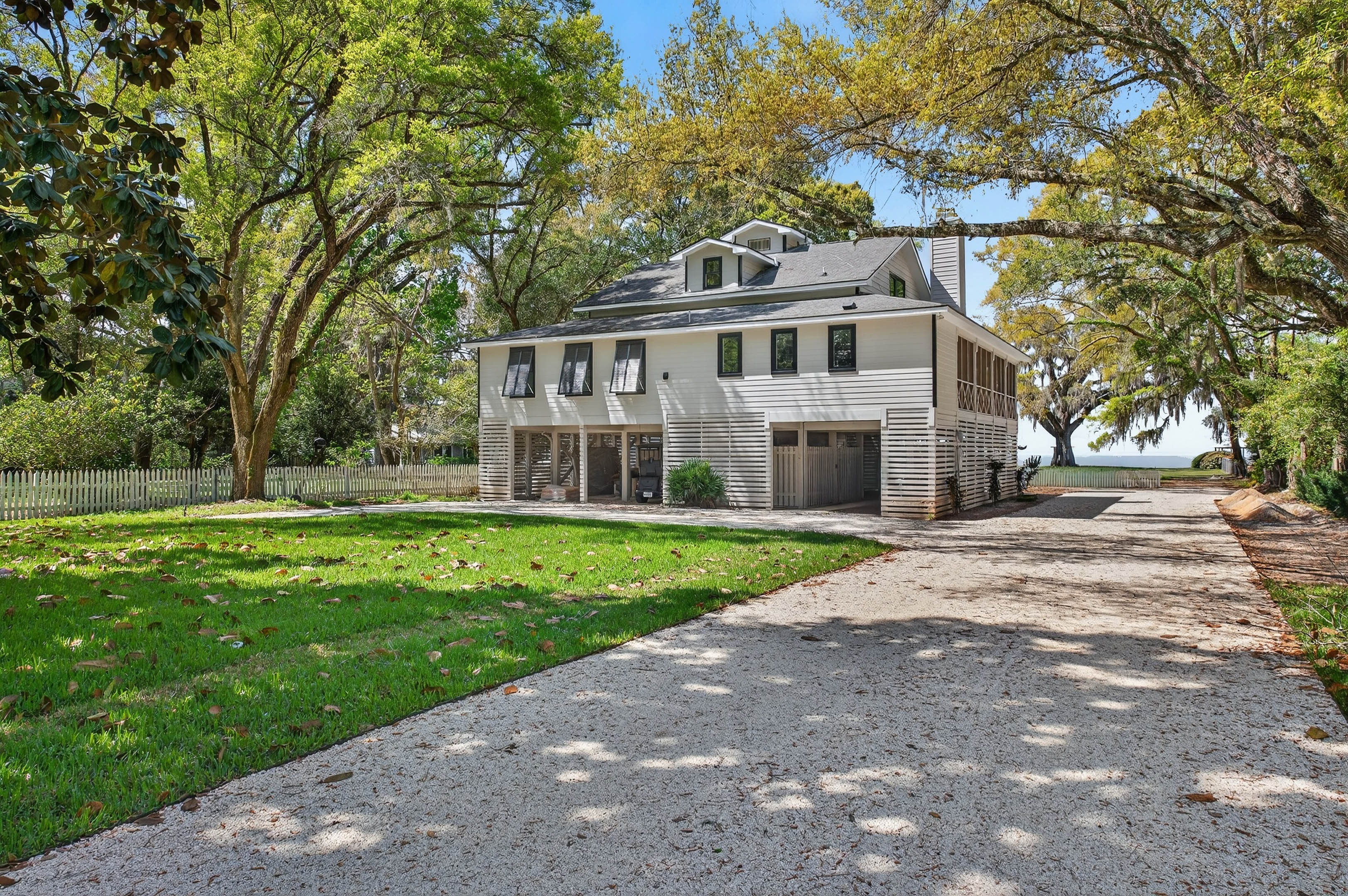 Driftwood Isle, a classic coastal home set beneath mature oaks with a private drive and bay just beyond