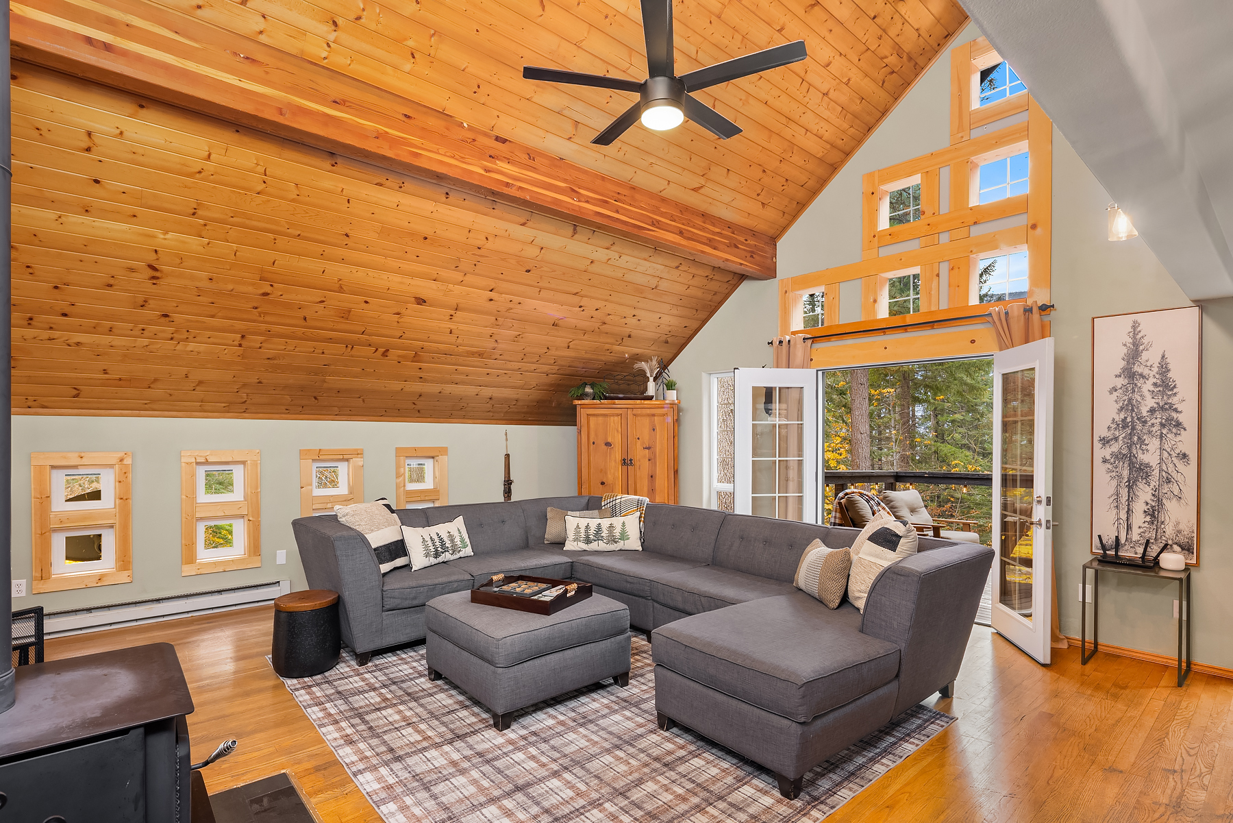Open living room and dining room with wood burning stove and French doors out to the upper deck