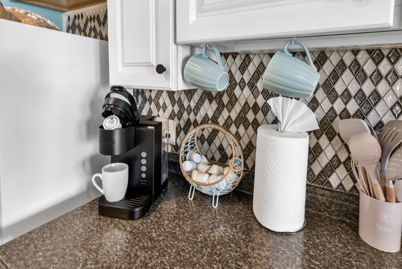 Kitchen counter with Keurig, mugs, paper towels, and cooking utensils — all the essentials ready to use