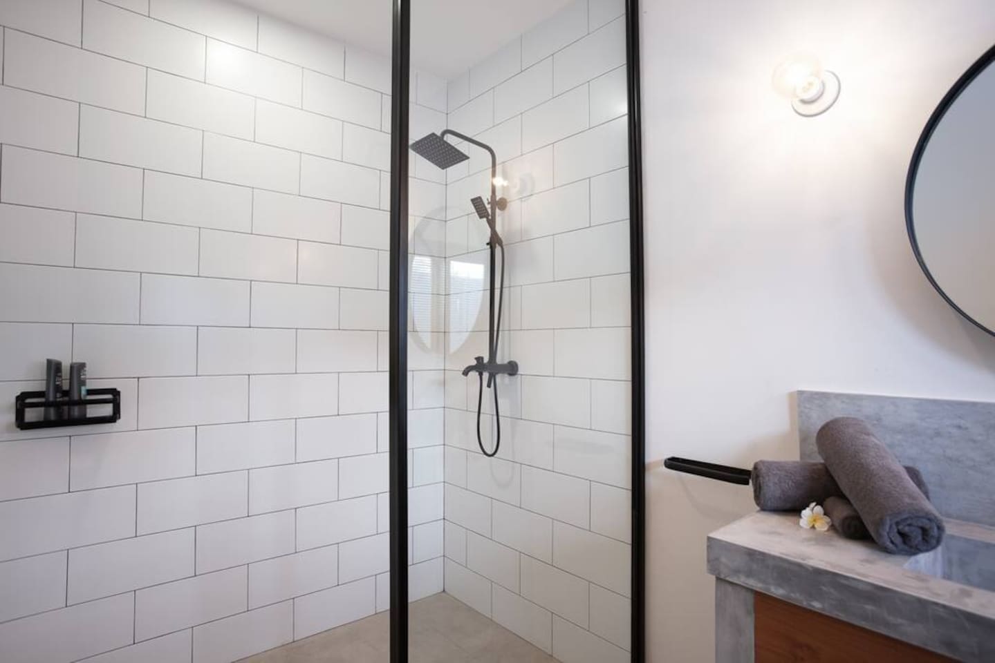A spacious shower equipped with all the necessary space, including shower gel, shampoo, and conditioner.