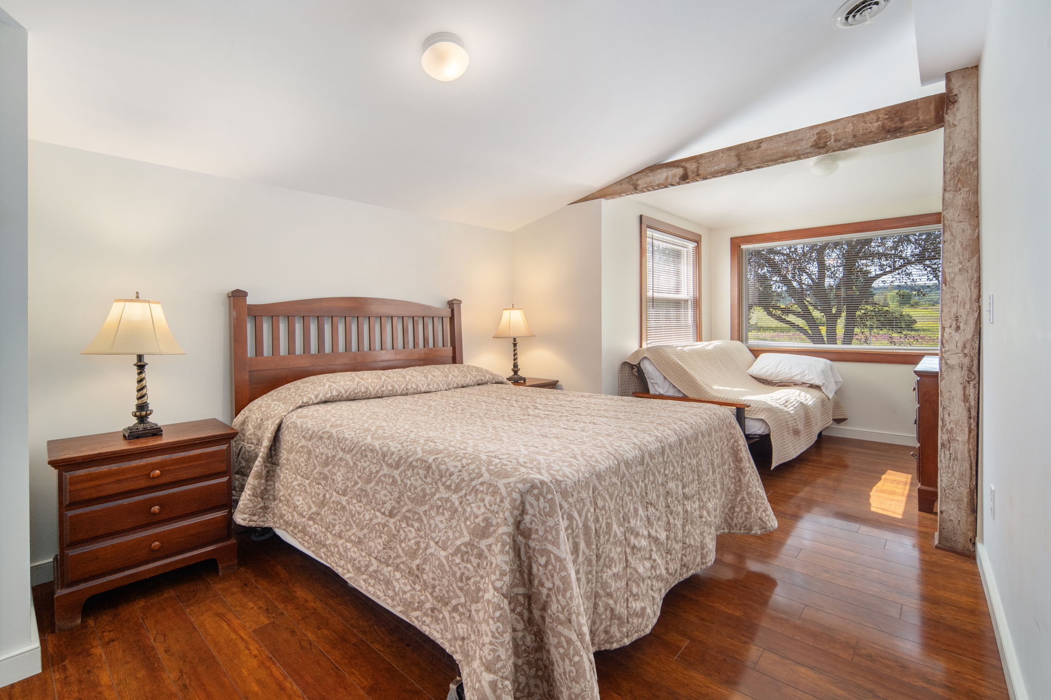 A spacious bedroom with a queen bed and a futon sitting area.