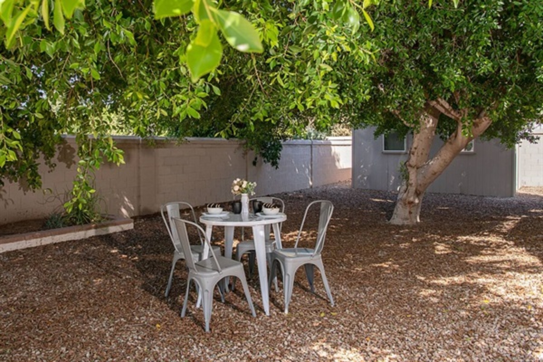 Enjoy peaceful mornings or shaded lunches at this charming backyard table nestled under mature trees and desert sky.