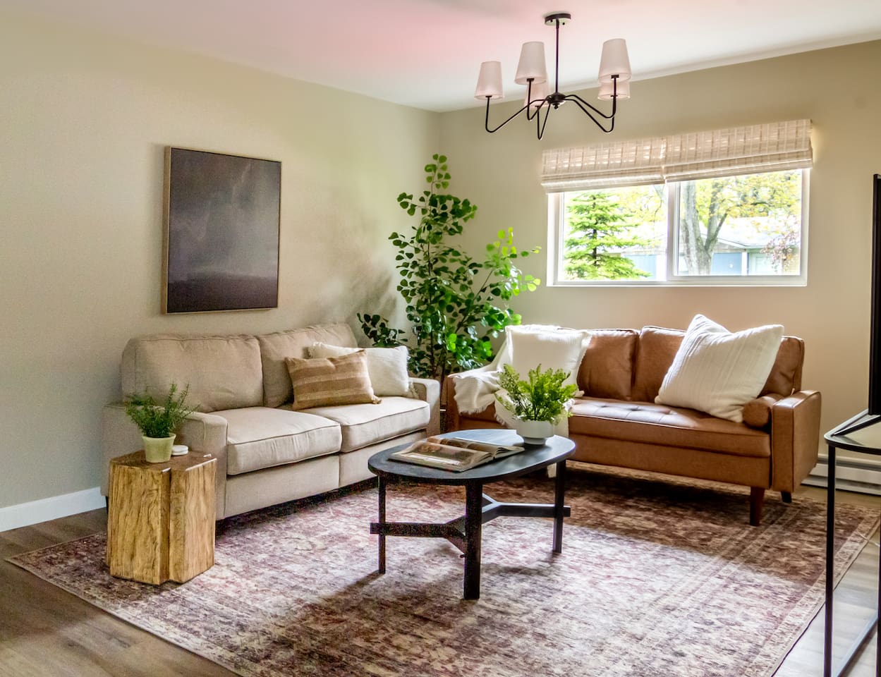 Warm leather and linen seating come together under a statement chandelier for a relaxed living room feel.