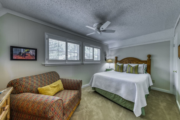 Unwind in the cozy bedroom featuring a comfortable queen-sized bed and a relaxing couch, perfect for a restful night or a quiet afternoon.