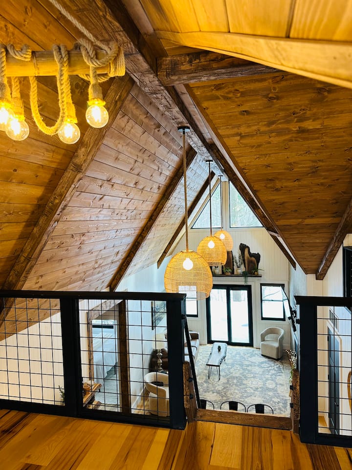 This dreamy second-story loft is accessible only by a ship’s ladder, adding an adventurous yet intimate feel. It features a king bed beneath a dramatic A-frame ceiling. Large triangular windows offer stunning views, making it the perfect hideaway.