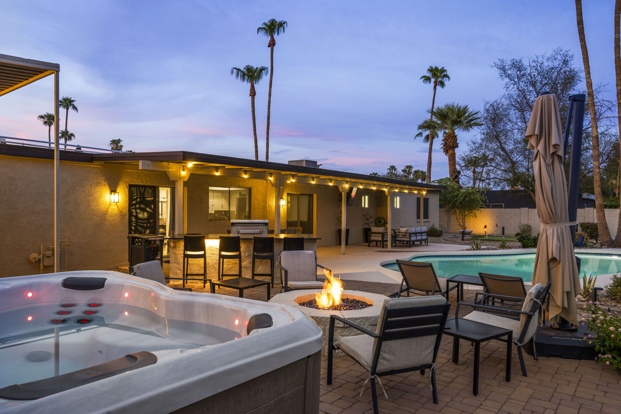 Private backyard with pool, spa, outdoor TV, BBQ, Putting Green, Corn Hole and multiple areas for dining and seating.