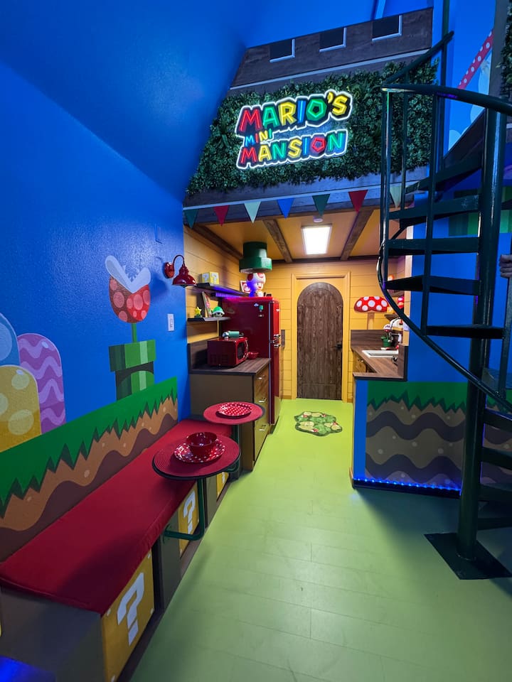 Magical Mario dining area at Mario's Mini Mansion, Clermont, FL! Red bench seating, spiral staircase, and glowing "Mario's Mini Mansion" sign make every meal feel like an adventure.