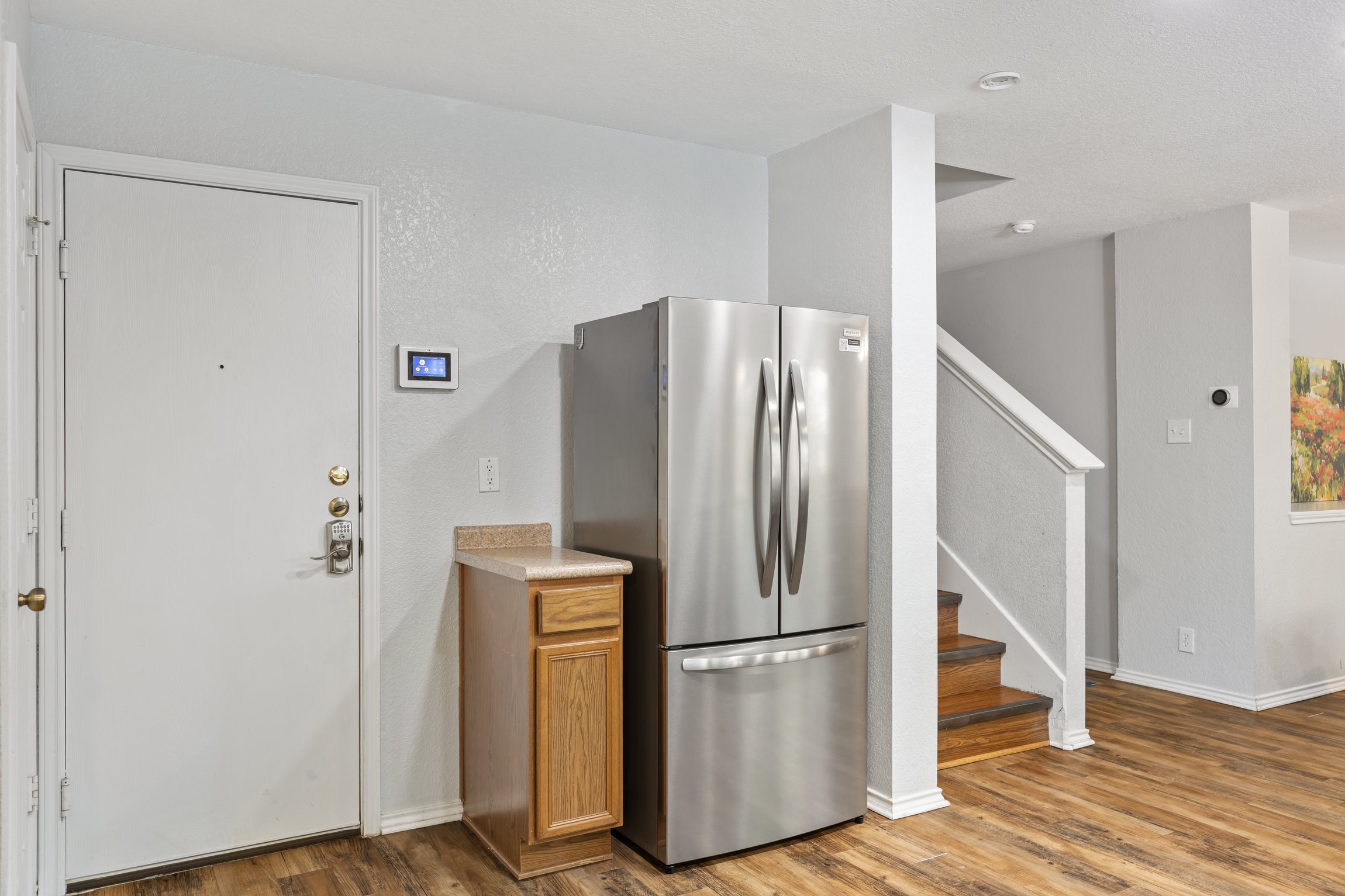 Stainless refrigerator on the main floor with staircase access to all 4 upstairs bedrooms. Open hardwood floor layout throughout — convenient and connected for families and groups in Northeast San Antonio.