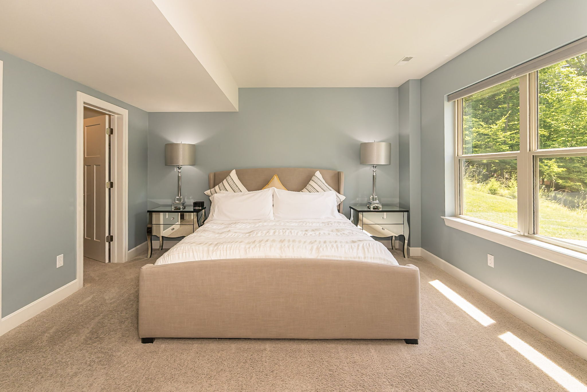 Lower-level king bedroom with large windows overlooking the woods.