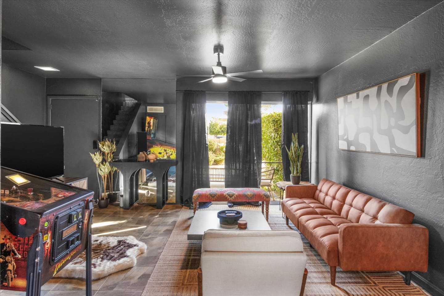 Living room with a leather sofa, arcade game, and moody lounge feel for relaxing indoors.