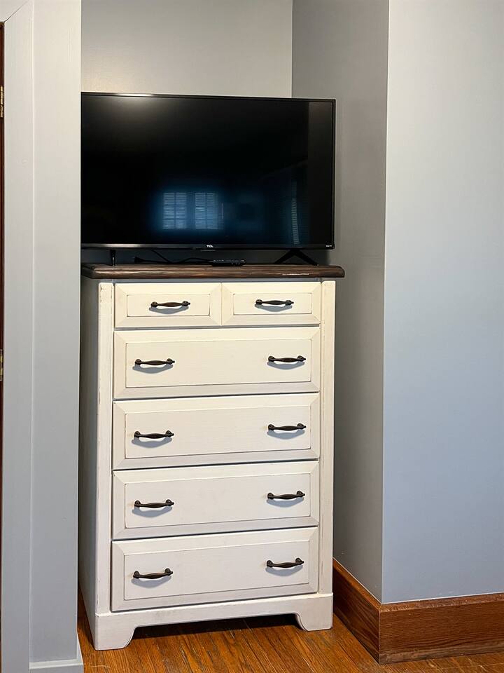 Stylish bedroom featuring a modern cabinet and a widescreen TV mounted on a sleek countertop—designed for contemporary comfort and functionality, offering a perfect balance of elegance and relaxation in a cozy space
