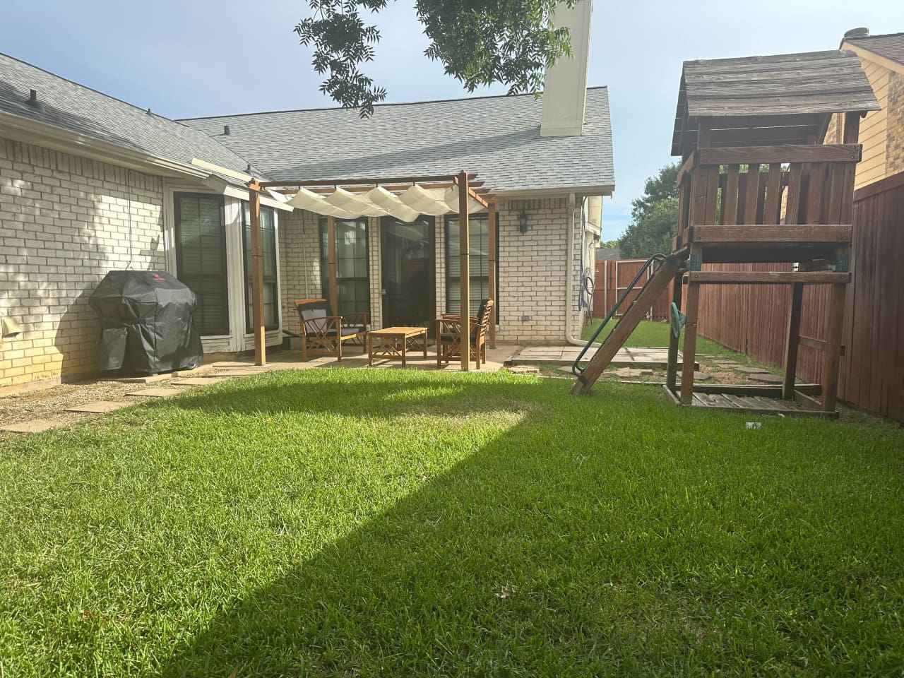 Private backyard with grill, seating, and playset — ideal for family fun.