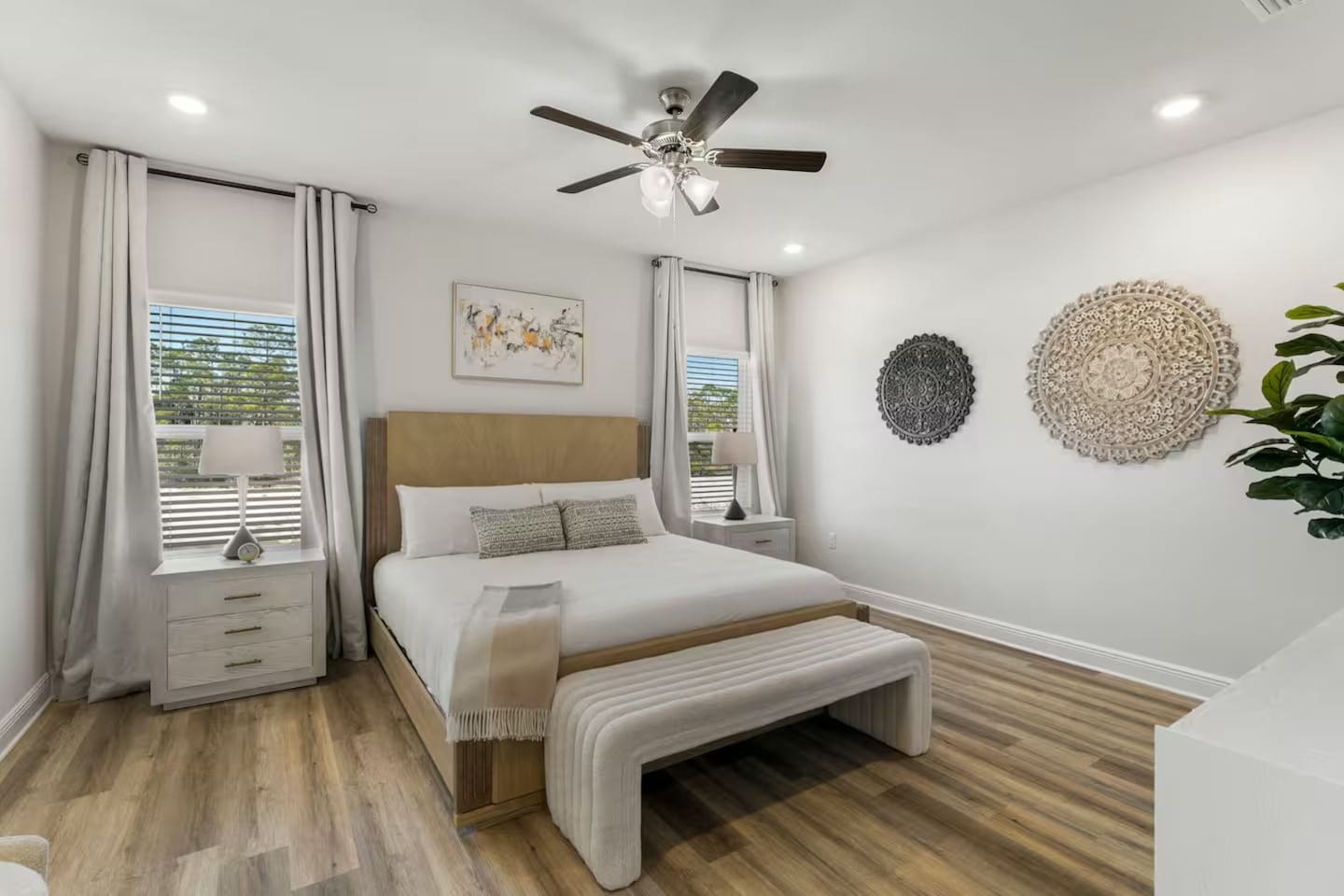 Comfort meets style with a ceiling fan, bedside lamps, and decorative artwork.