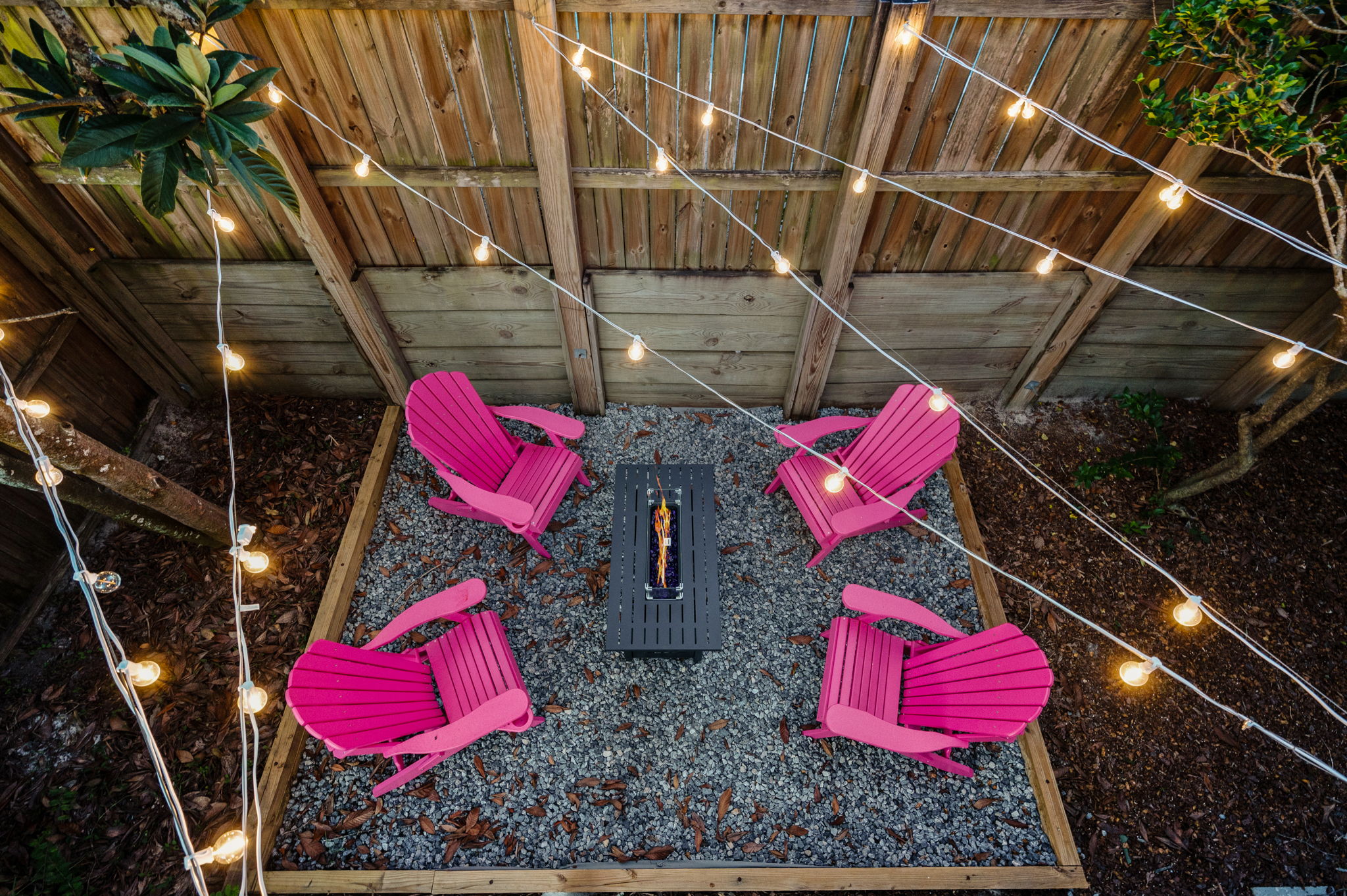 Another view of the firepit area, complete with pink chairs and twinkling string lights overhead. It’s a perfect spot for cozy evenings outdoors, with the lights adding a magical touch!