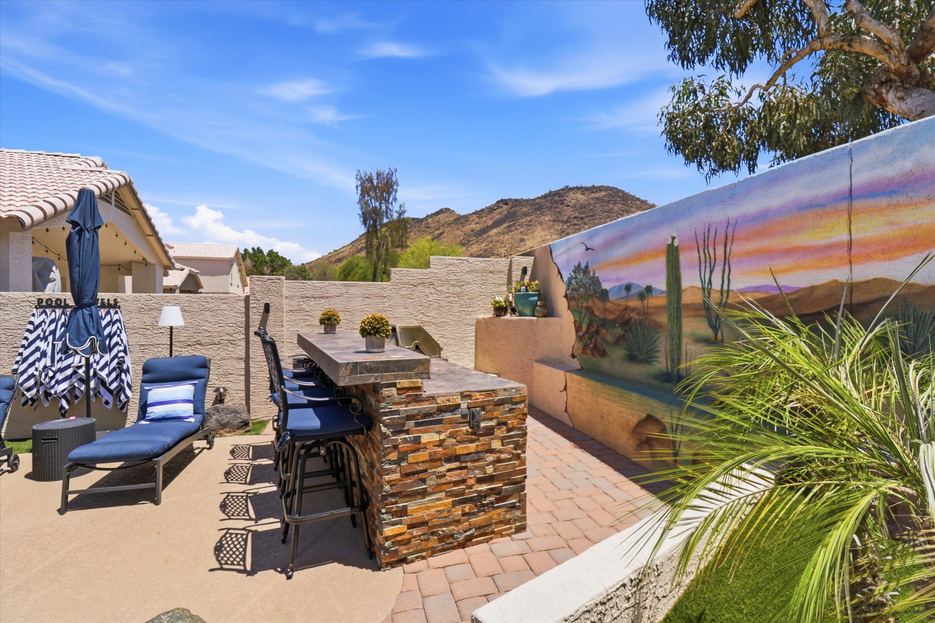 Outdoor bar area with lounge seating, desert mural, and mountain views for relaxed poolside downtime.
