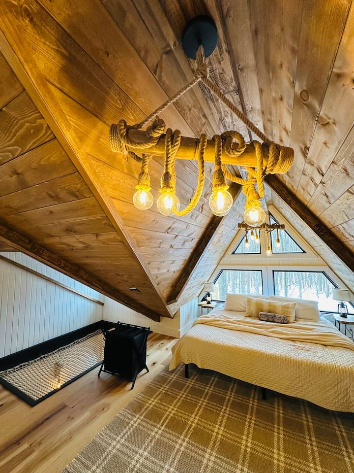 This dreamy second-story loft is accessible only by a ship’s ladder, adding an adventurous yet intimate feel. It features a king bed beneath a dramatic A-frame ceiling. Large triangular windows offer stunning views, making it the perfect hideaway.