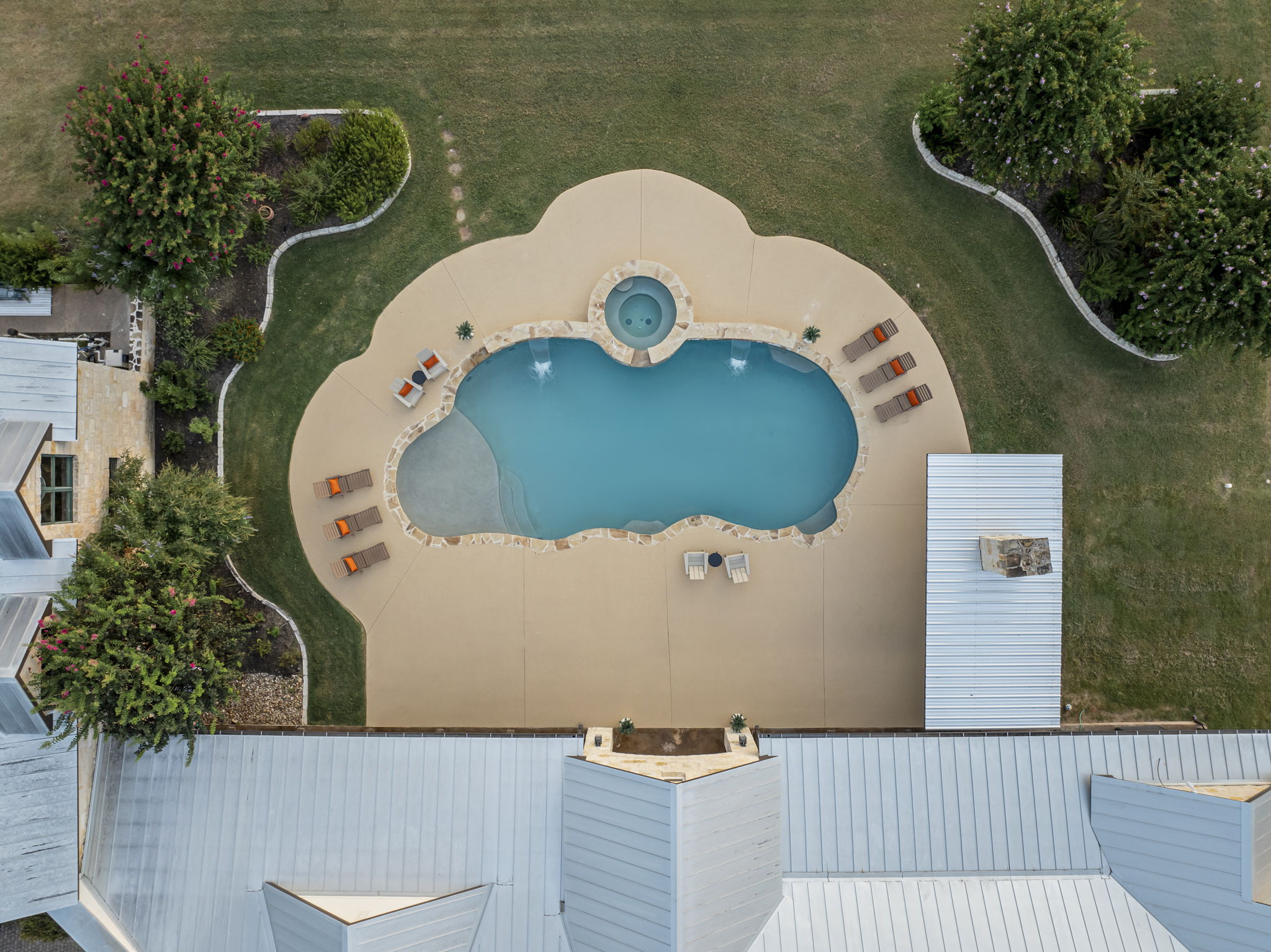 Bird's-eye perspective of a beautiful home and its expansive grounds, featuring a sparkling swimming pool and hot tub.
